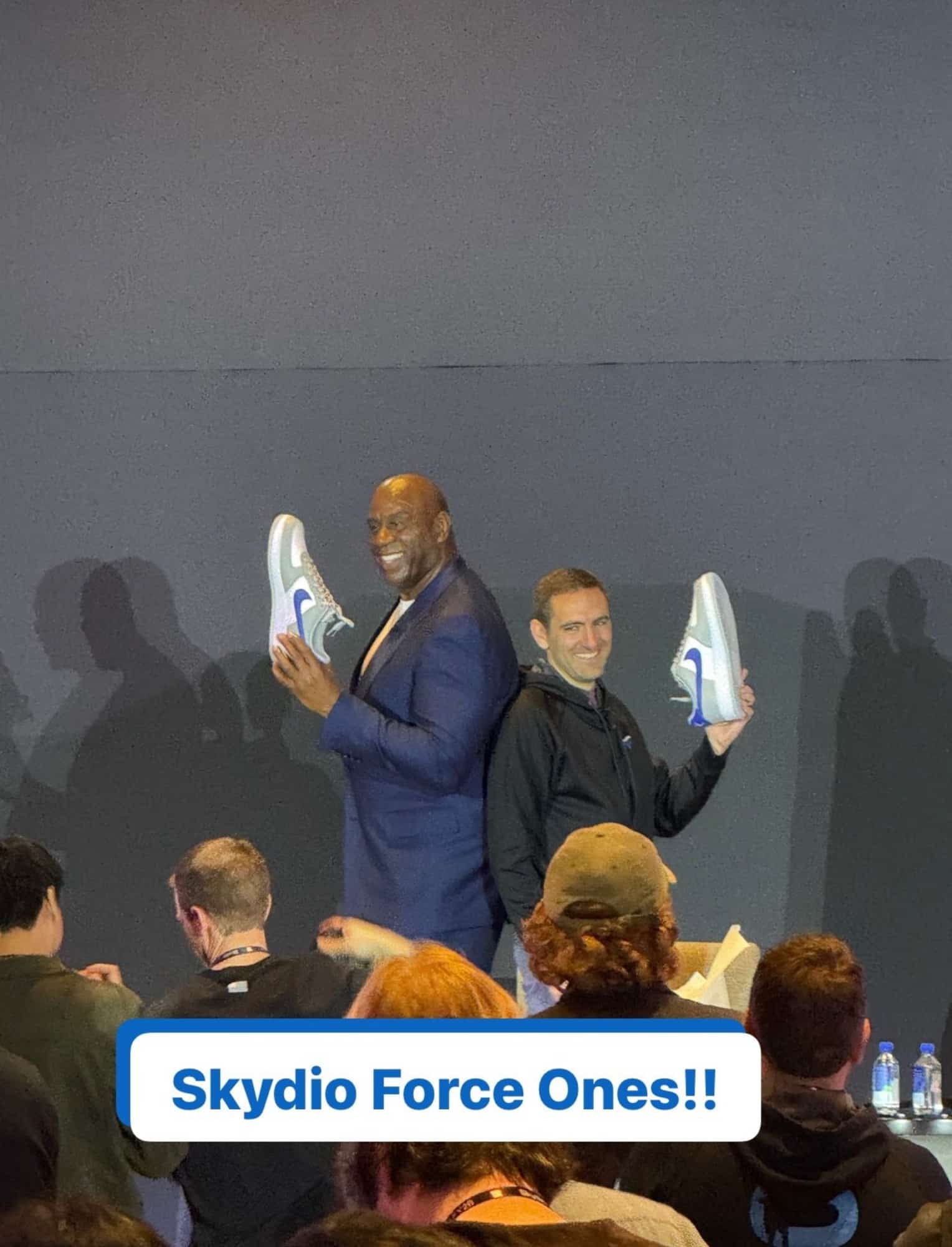 Two speakers on stage each raising one sneaker, captioned Skydio Force Ones.