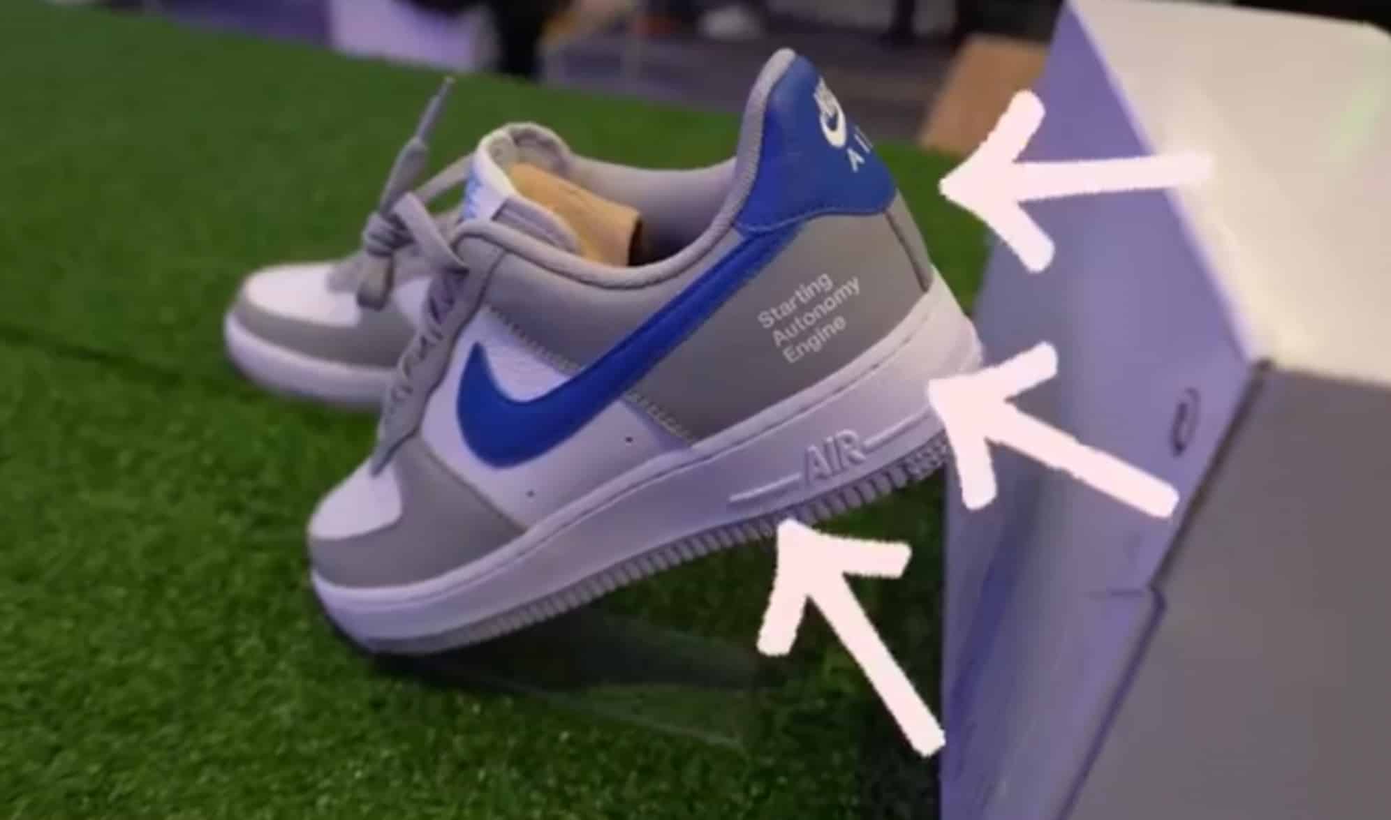 Custom grey and blue Nike sneaker with arrows pointing at embroidered details.