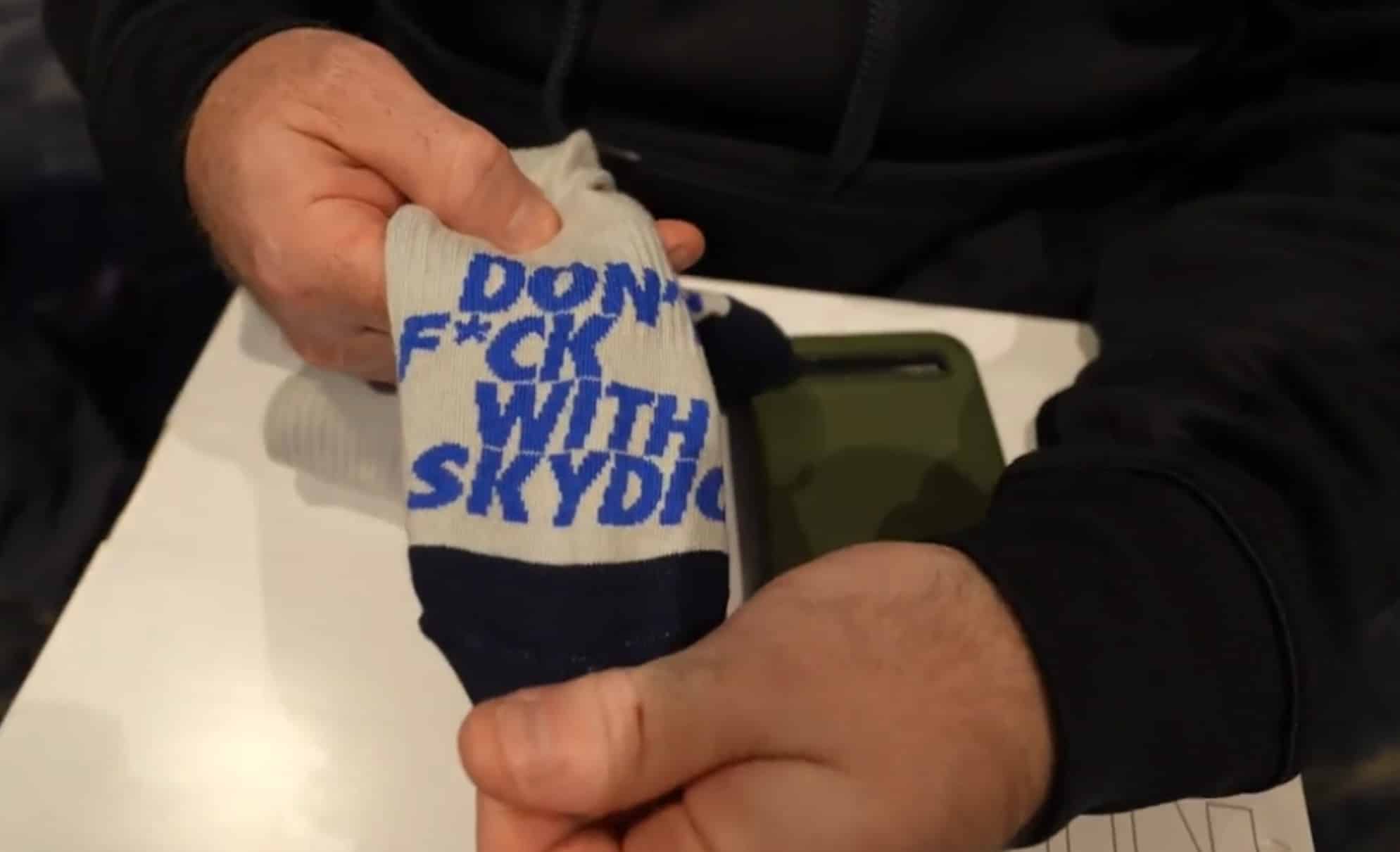 Hand holding a white sock printed with a defiant slogan in blue lettering.