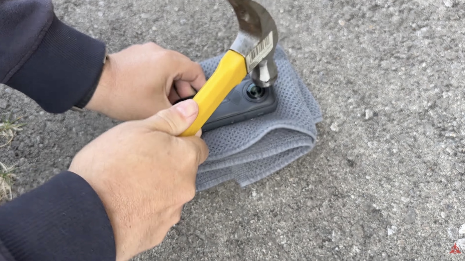 A hammer strikes the X5 lens on concrete during a durability test.