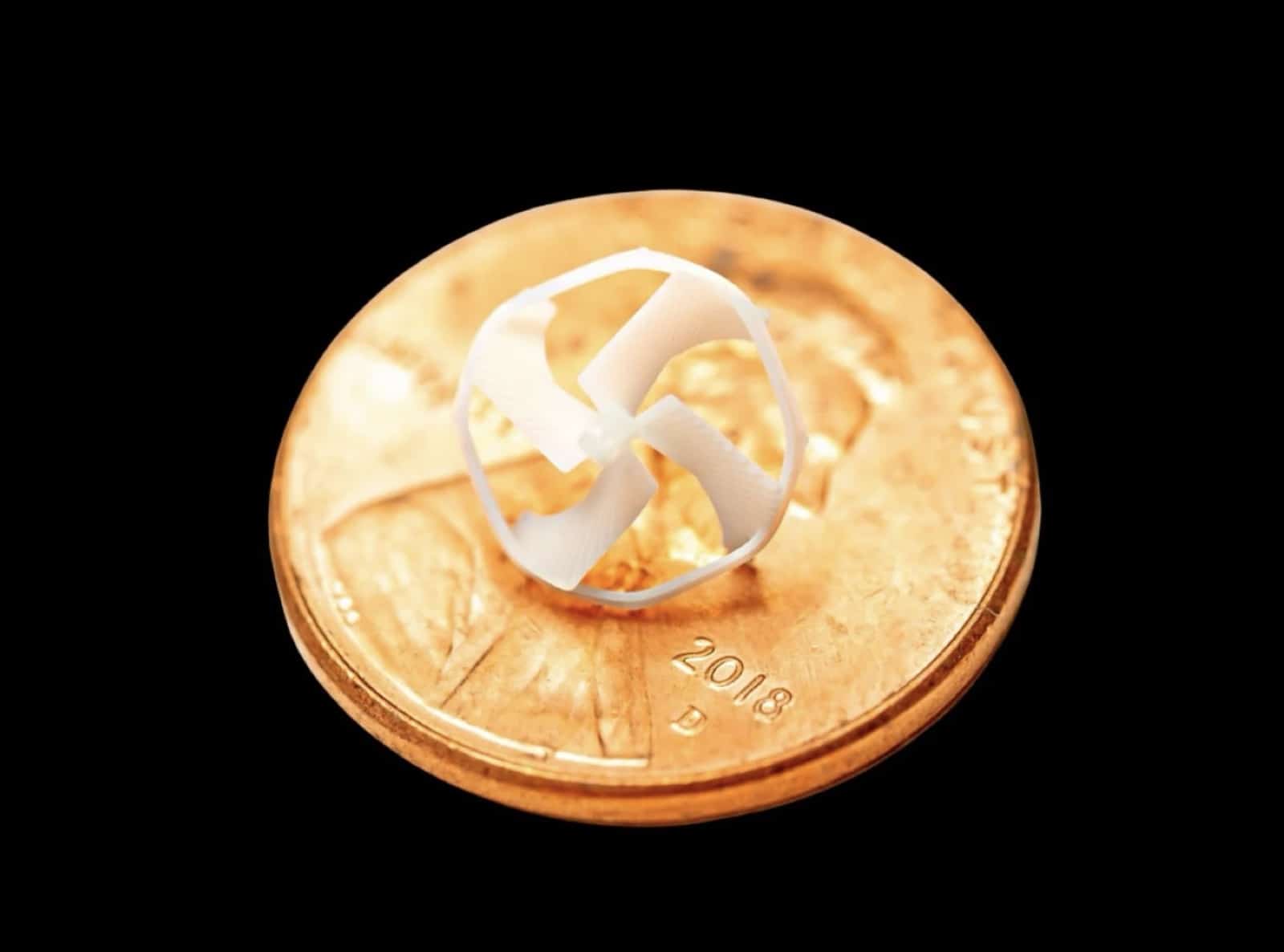 The micro-drone resting on a U.S. penny to show its scale.