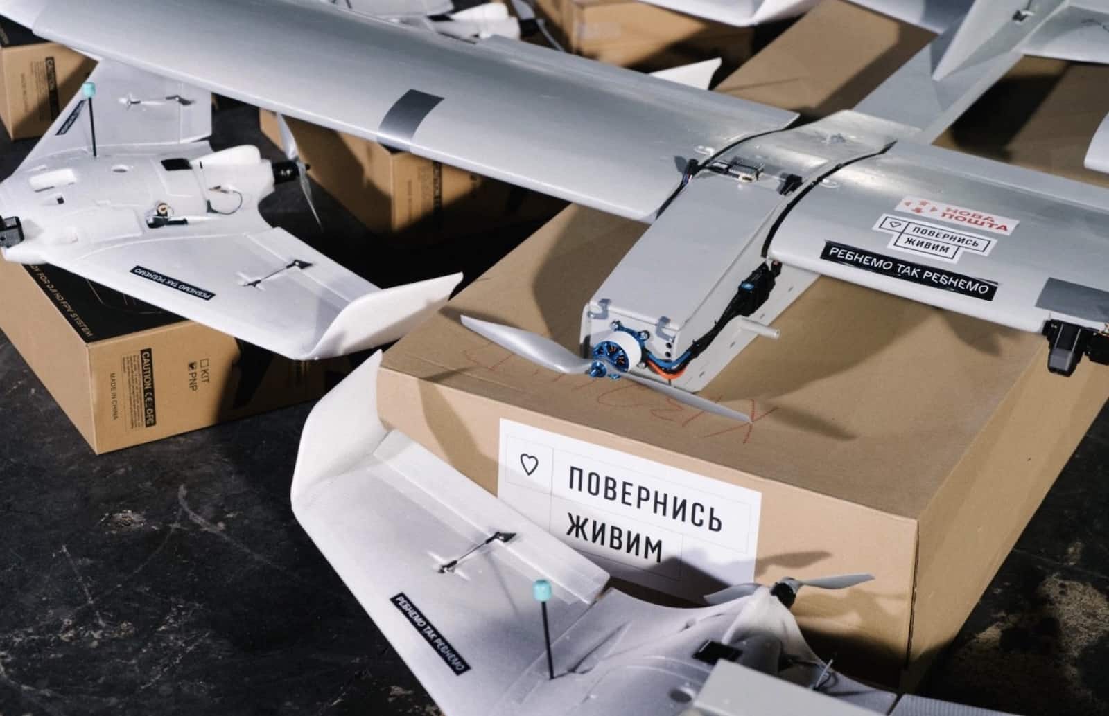 Foam fixed-wing drones packed in cardboard boxes carrying Ukrainian come back alive labels.