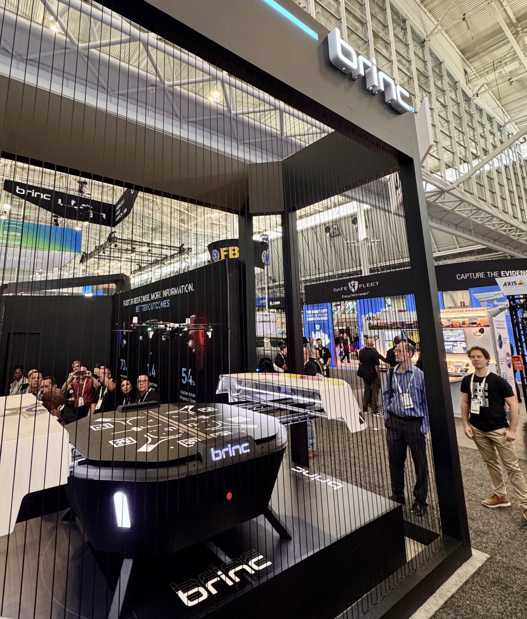 BRINC trade show booth with a black dock and drone under the illuminated logo.