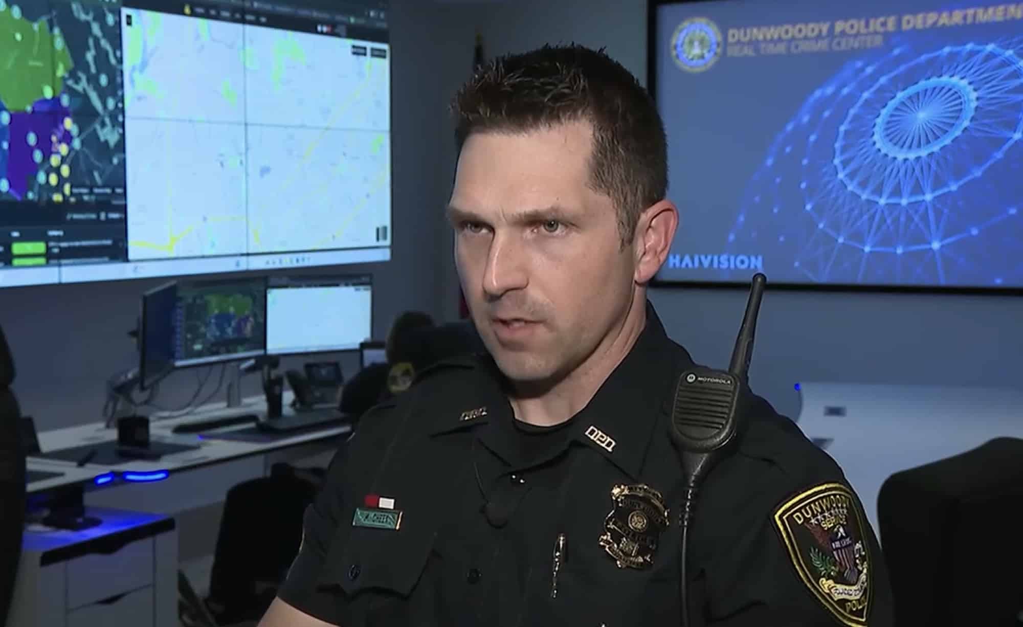 A police sergeant speaks inside the real-time crime center ringed by monitors.