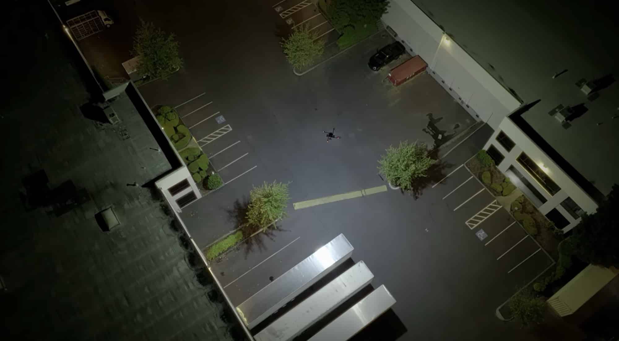 Aerial night view of a parking lot and building lit from above.
