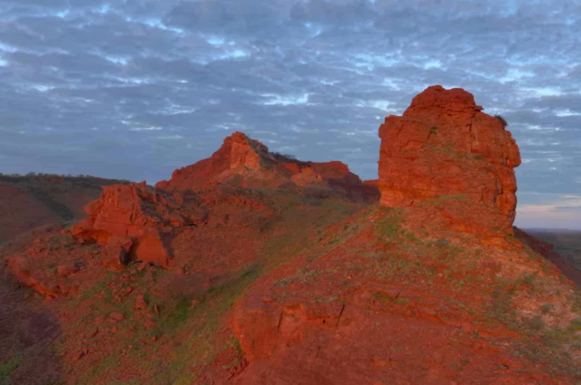 Aerial view of red sandstone outcrops rising from the Australian outback at first light.
