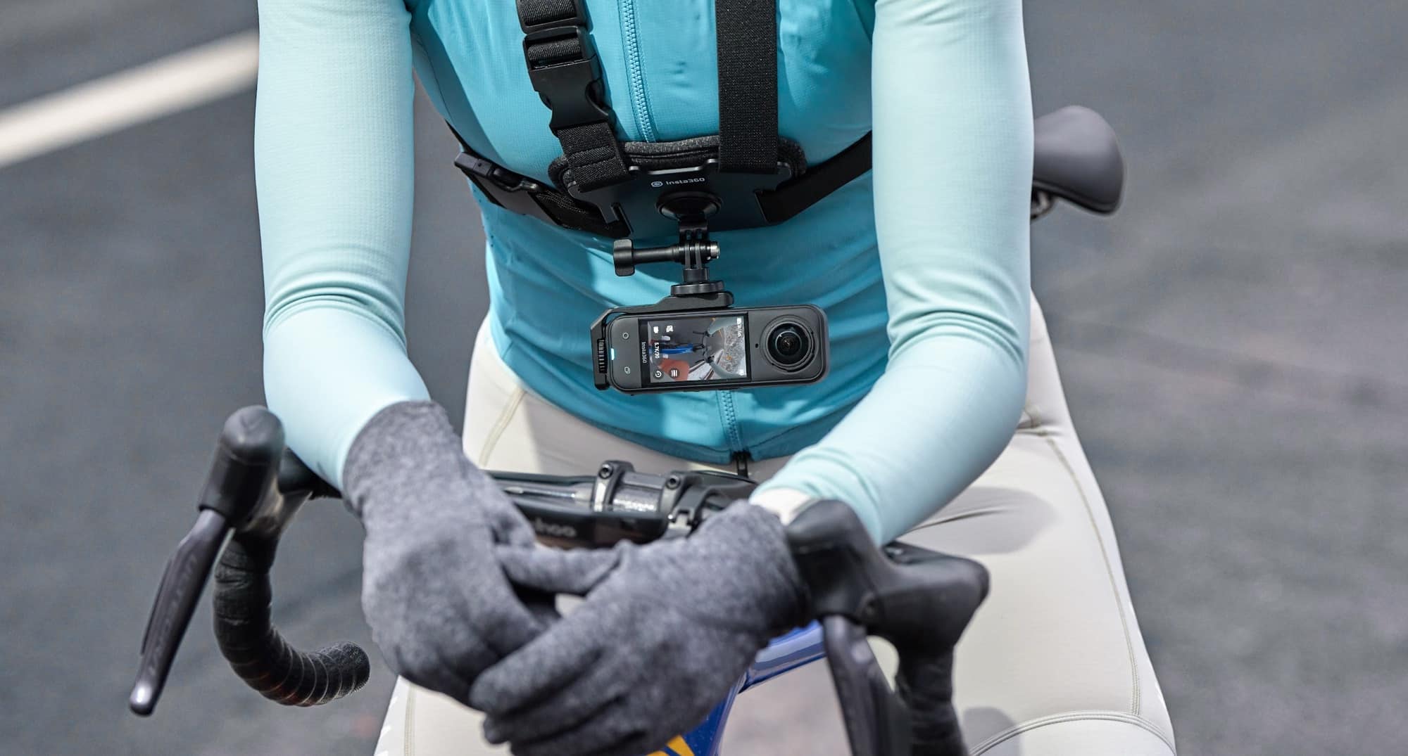 A cyclist grips drop bars with the 360 camera strapped to a chest harness.