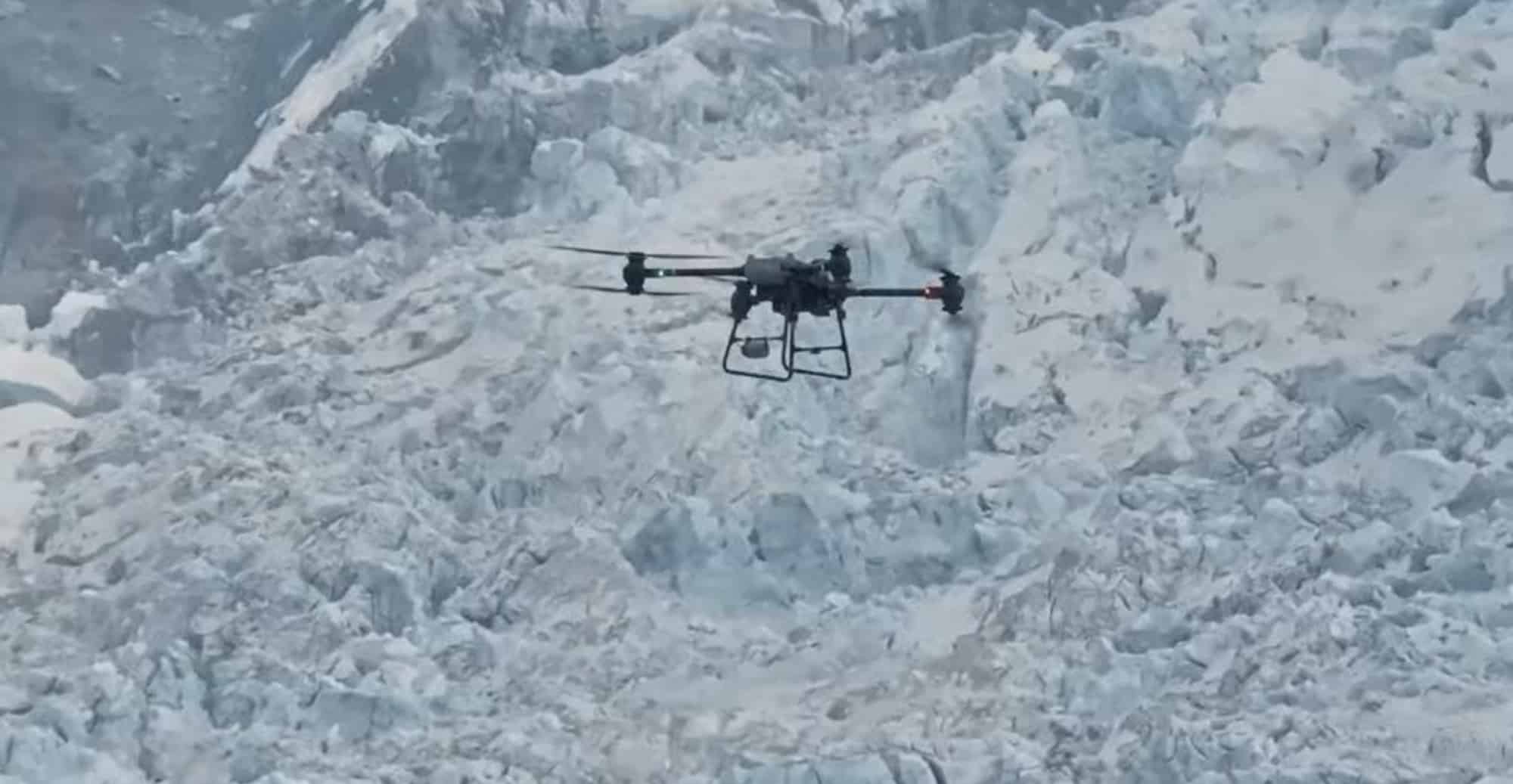 Cargo drone hovering low over a jumbled expanse of glacier ice and snow.
