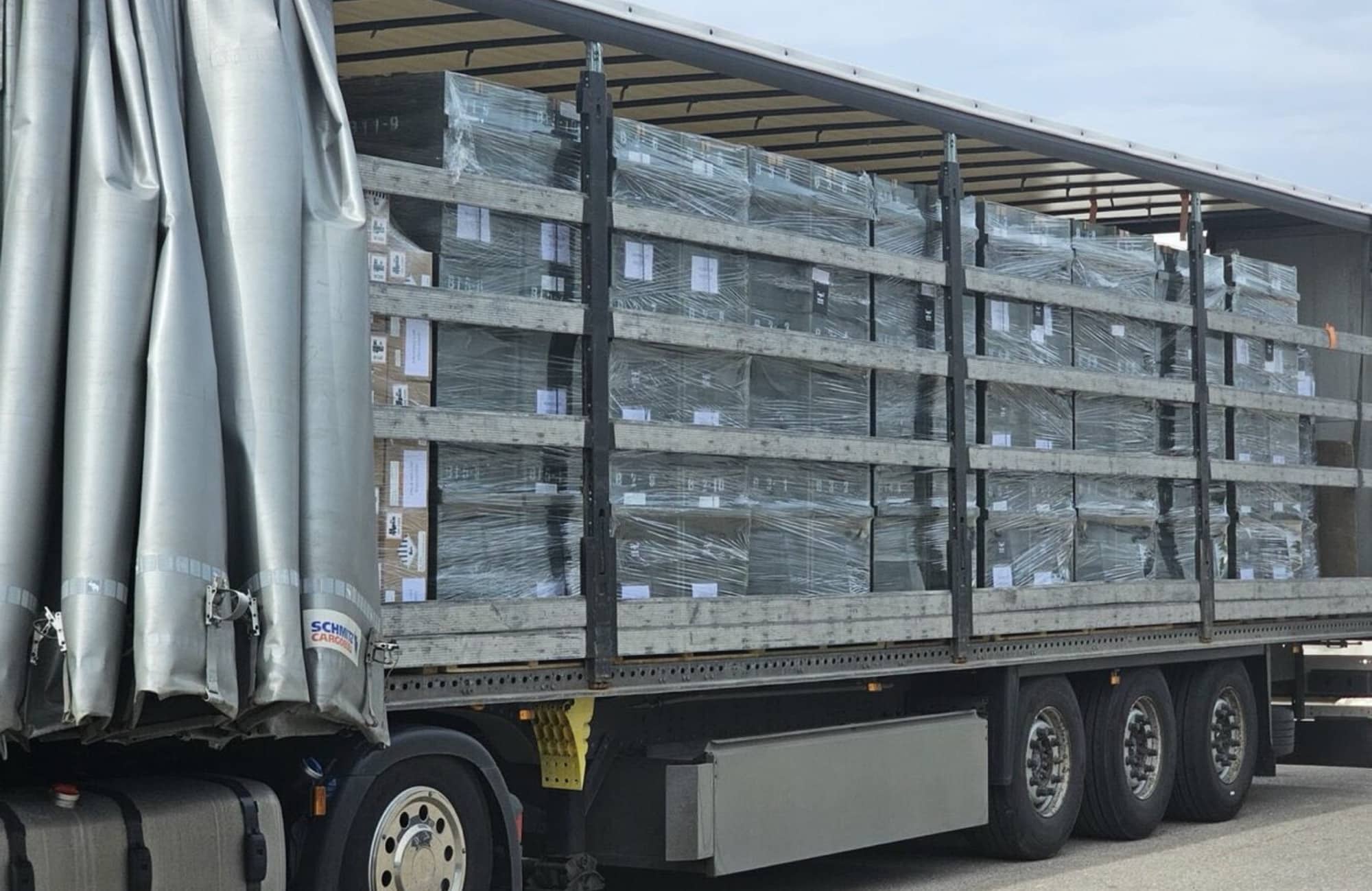 A curtain-side trailer packed with stacked pallets of boxed drones ready for shipment.