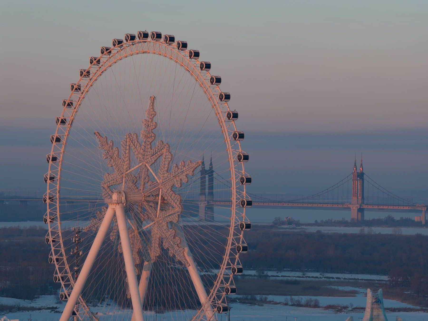 A tight 168mm crop of the Ferris wheel with a suspension bridge behind.