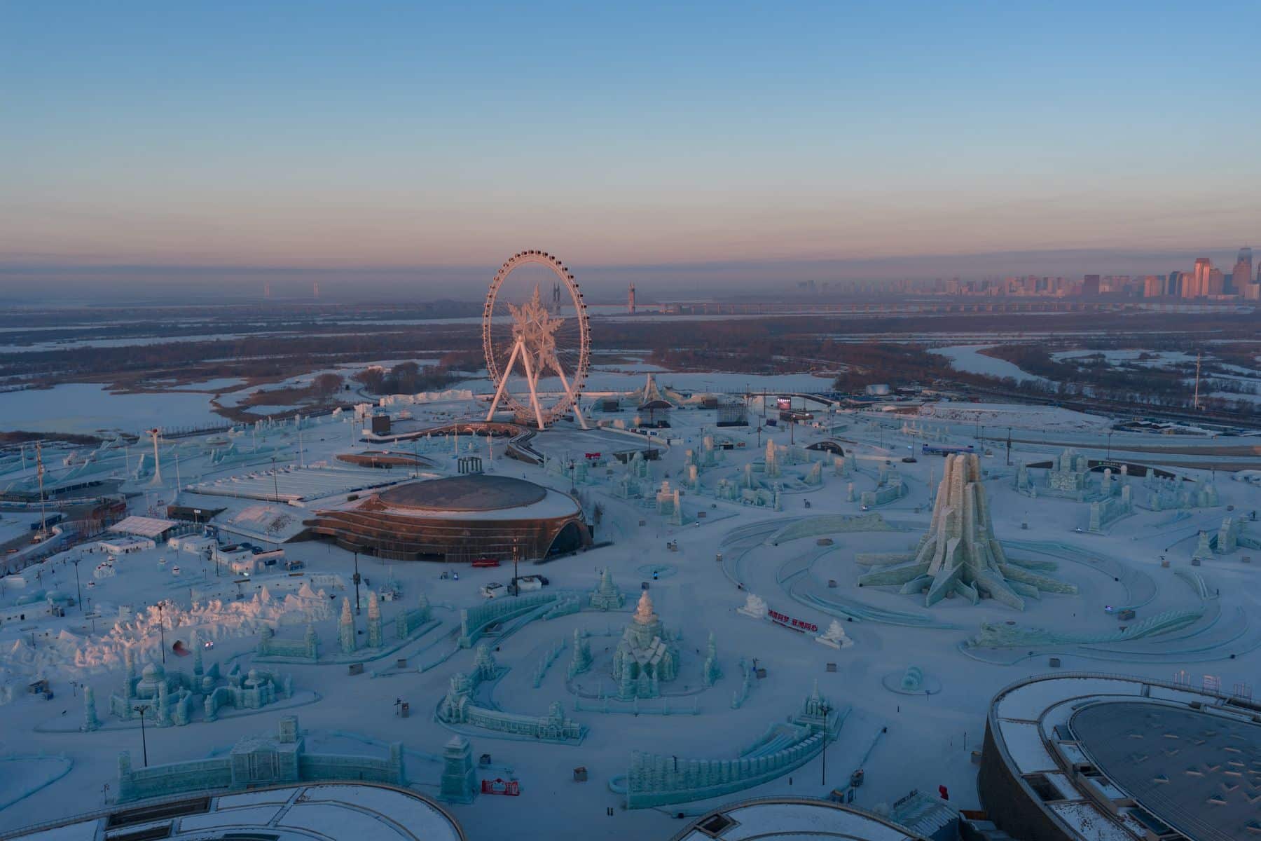 Wide 28mm view of an ice festival with a Ferris wheel and frozen river.
