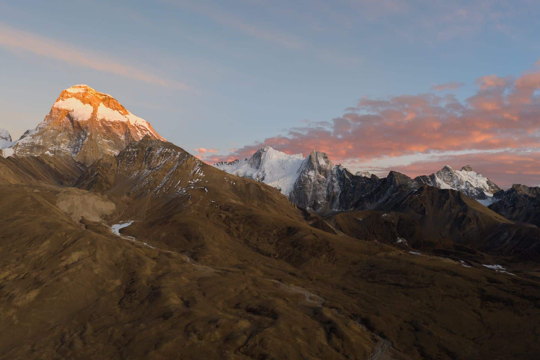 Wide 28mm golden-hour view along a ridge toward a sunlit summit.