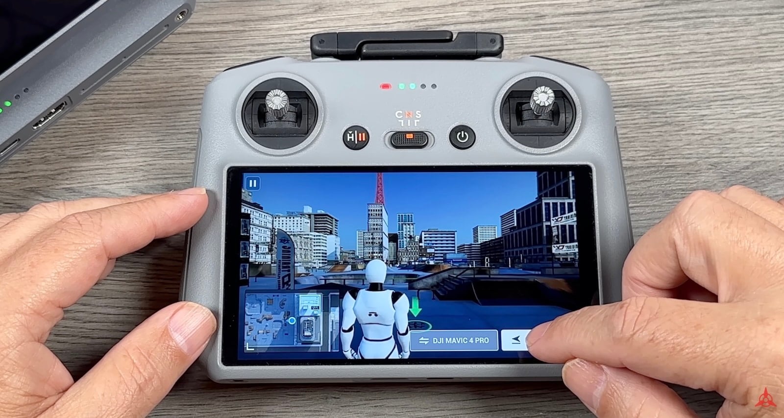 Hands hold the controller running the built-in flight simulator through a virtual city.