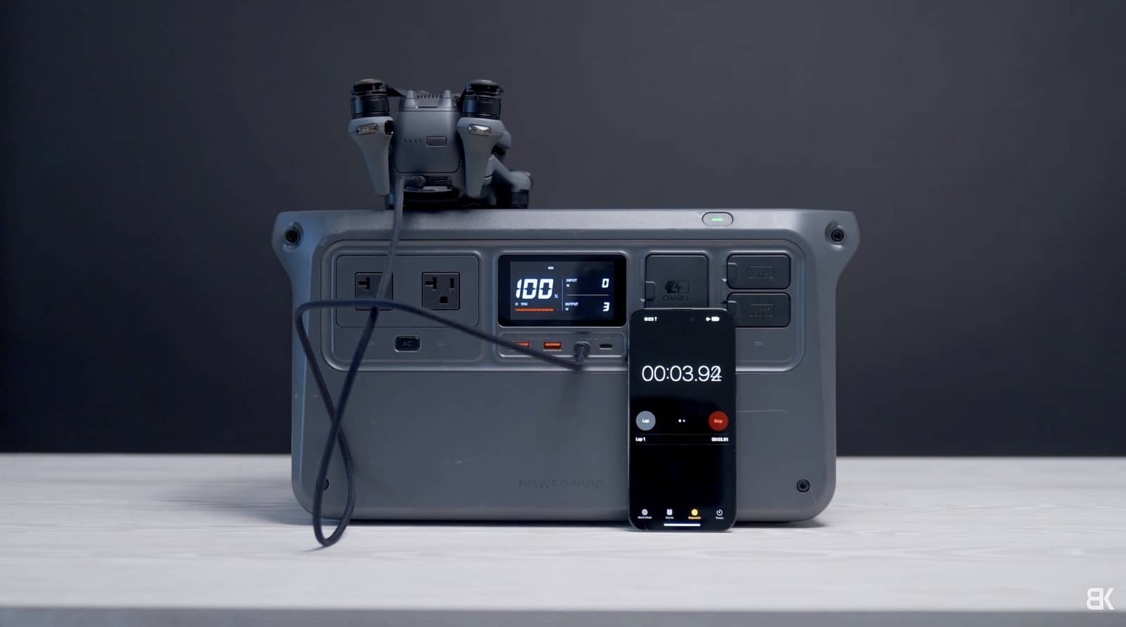 The drone and its controller charge from a portable power station reading 100 percent.