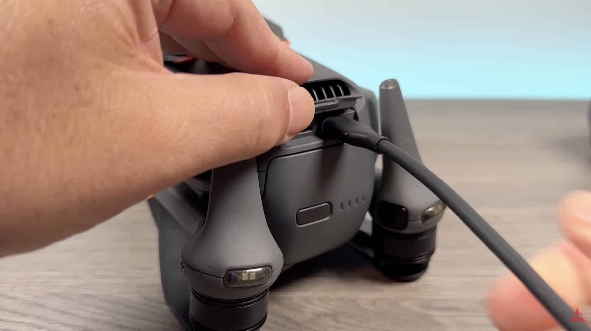 A hand plugs a USB-C cable into the side of a folded Mavic 4 Pro.