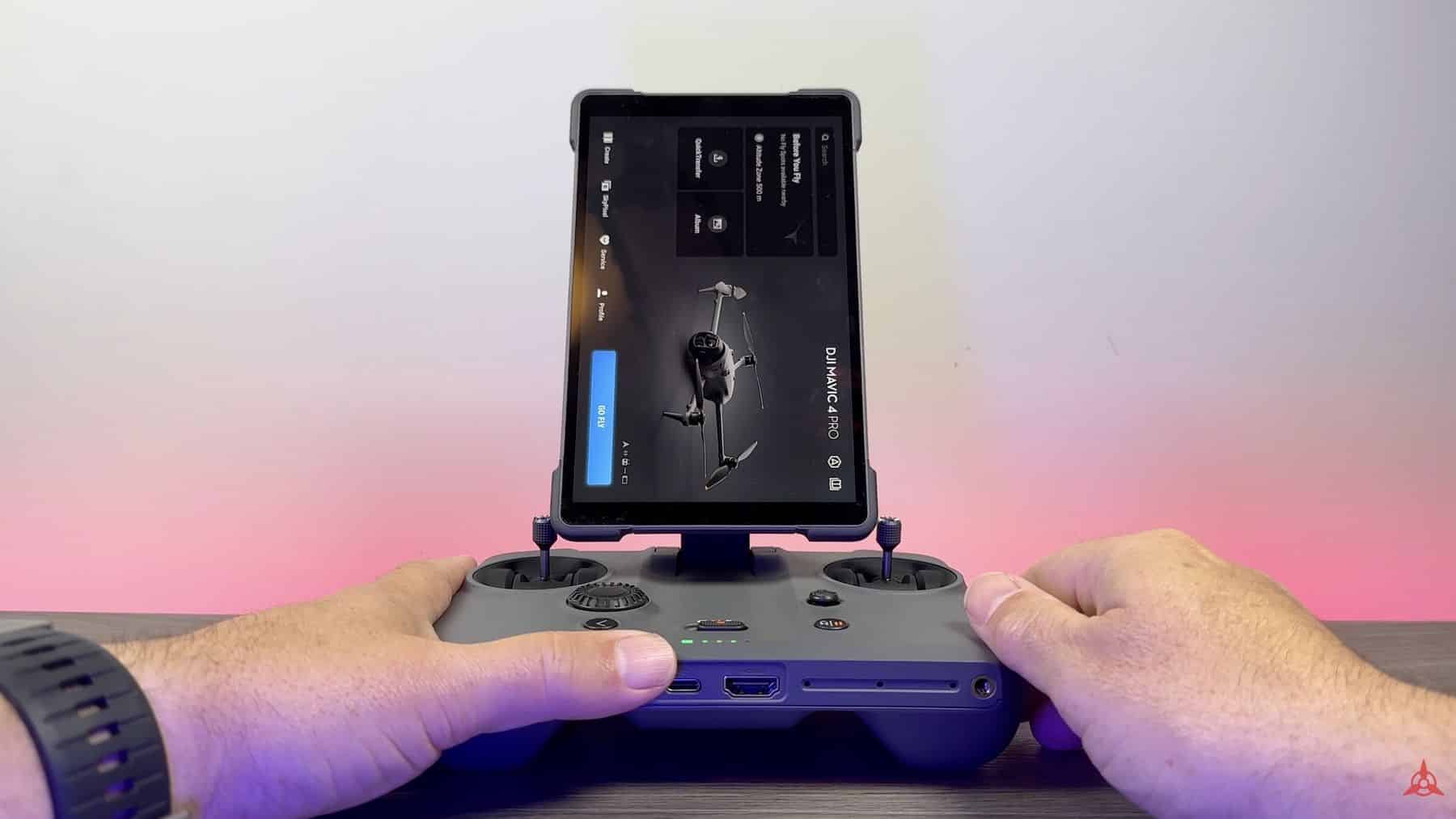 Hands hold a screen controller against a pink and purple lit background.