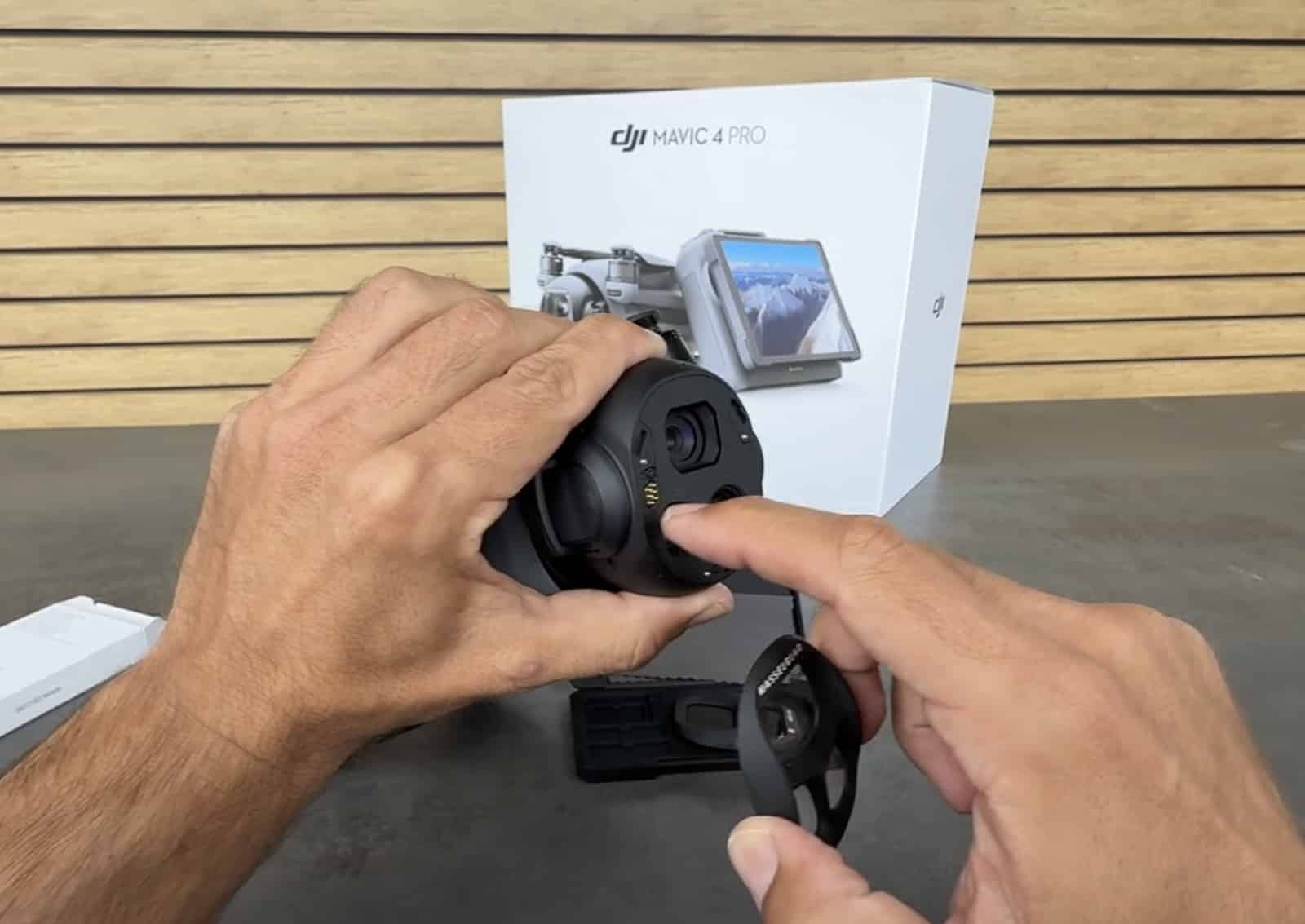 Bare Mavic 4 Pro gimbal in hand with its lenses and gold contacts exposed.