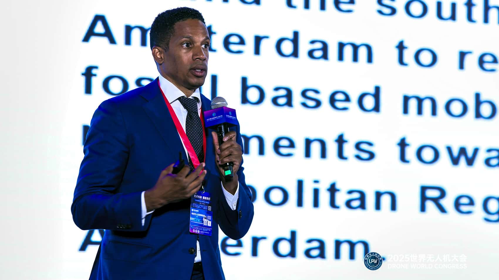 Presenter with a microphone speaks in front of a slide on Amsterdam mobility.