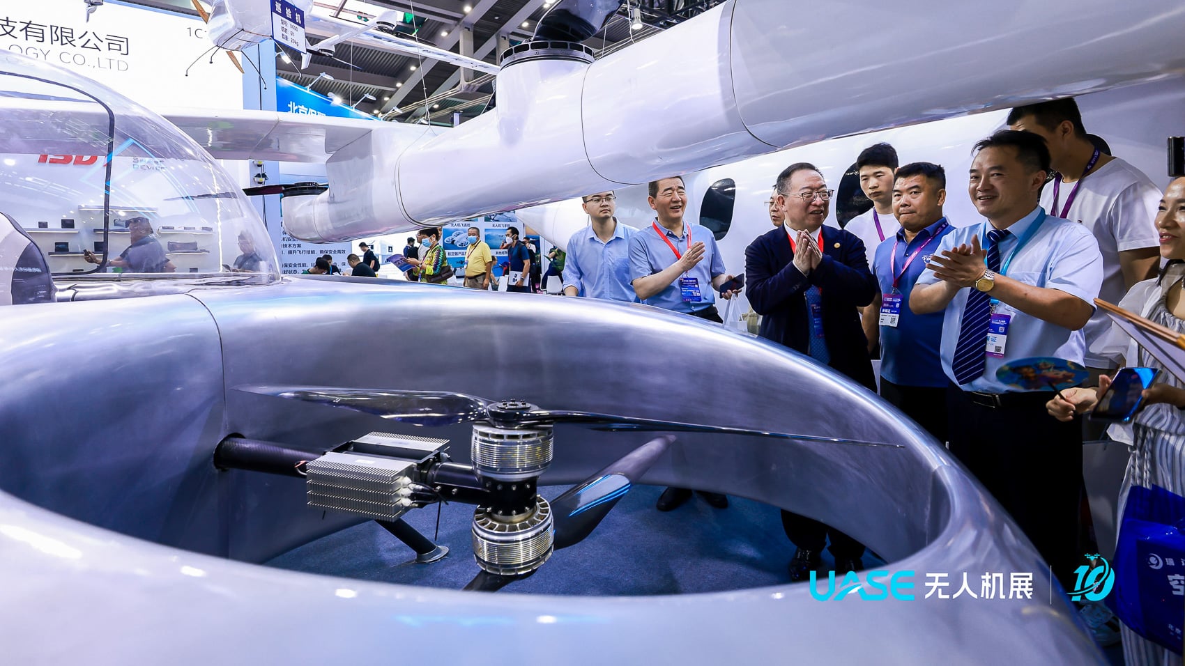 Visitors crowd a booth where a quadcopter sits inside a white automated dock.