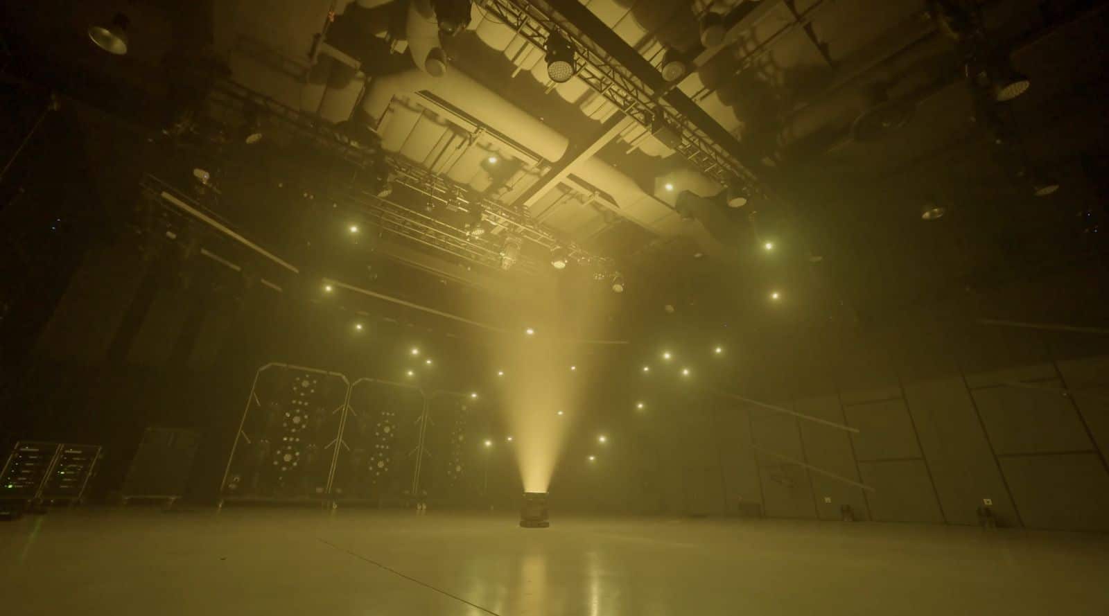 A single beam payload cuts down through golden haze in the demonstration studio.
