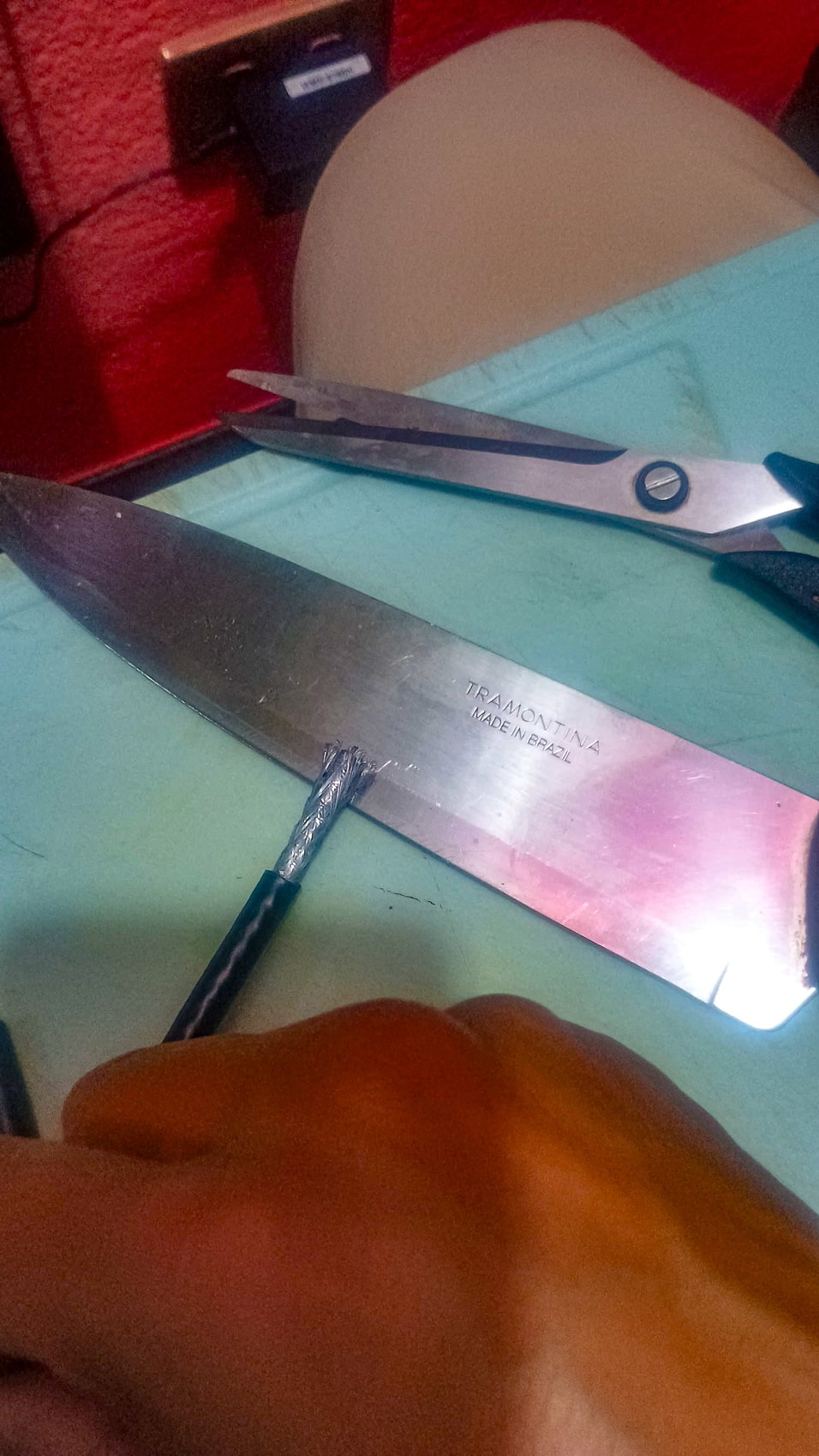 A stripped coaxial cable lies beside scissors and a kitchen knife on a work surface.
