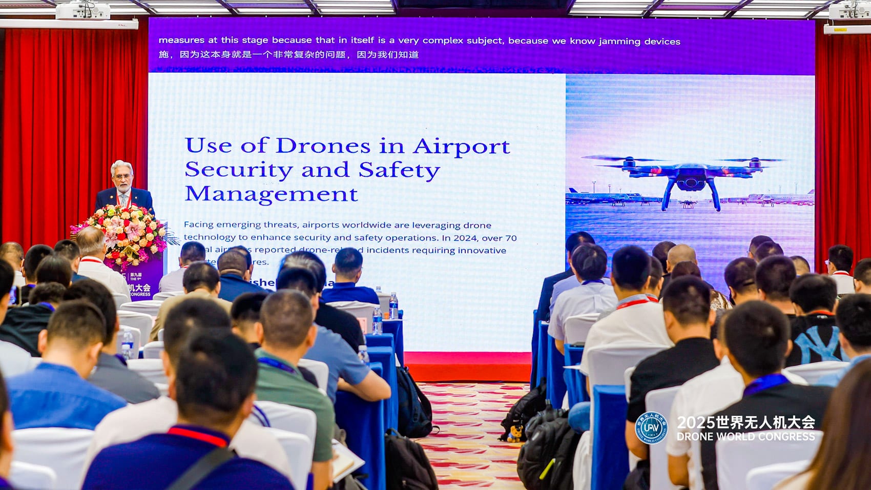 Slide on drones for airport security and safety faces a seated audience.