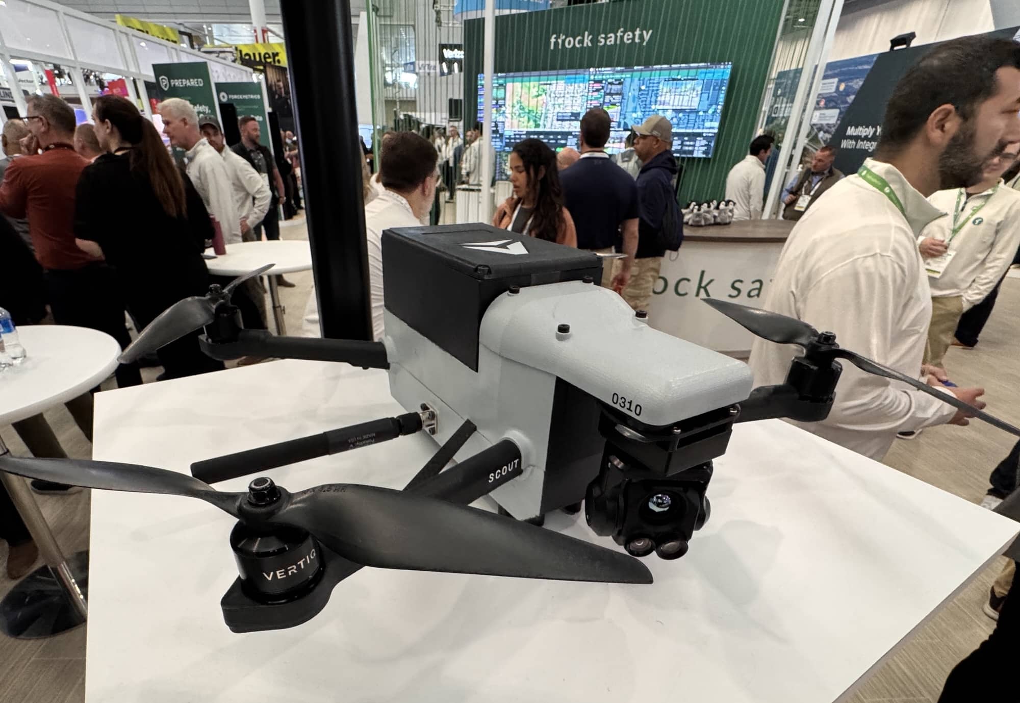 A white first-responder quadcopter sits on a table at the Flock Safety trade show booth.