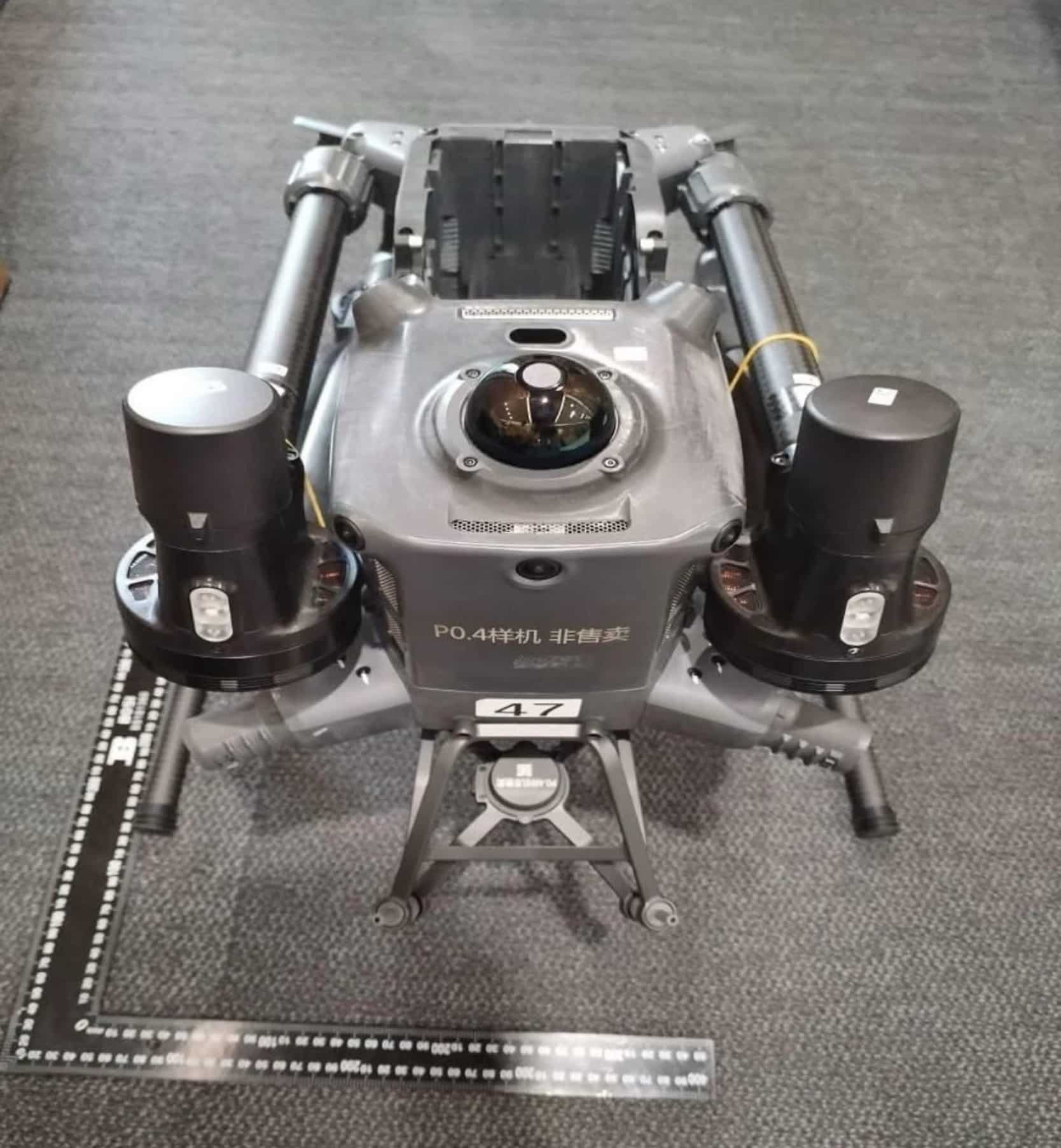 Prototype enterprise drone photographed beside a ruler on office carpet.
