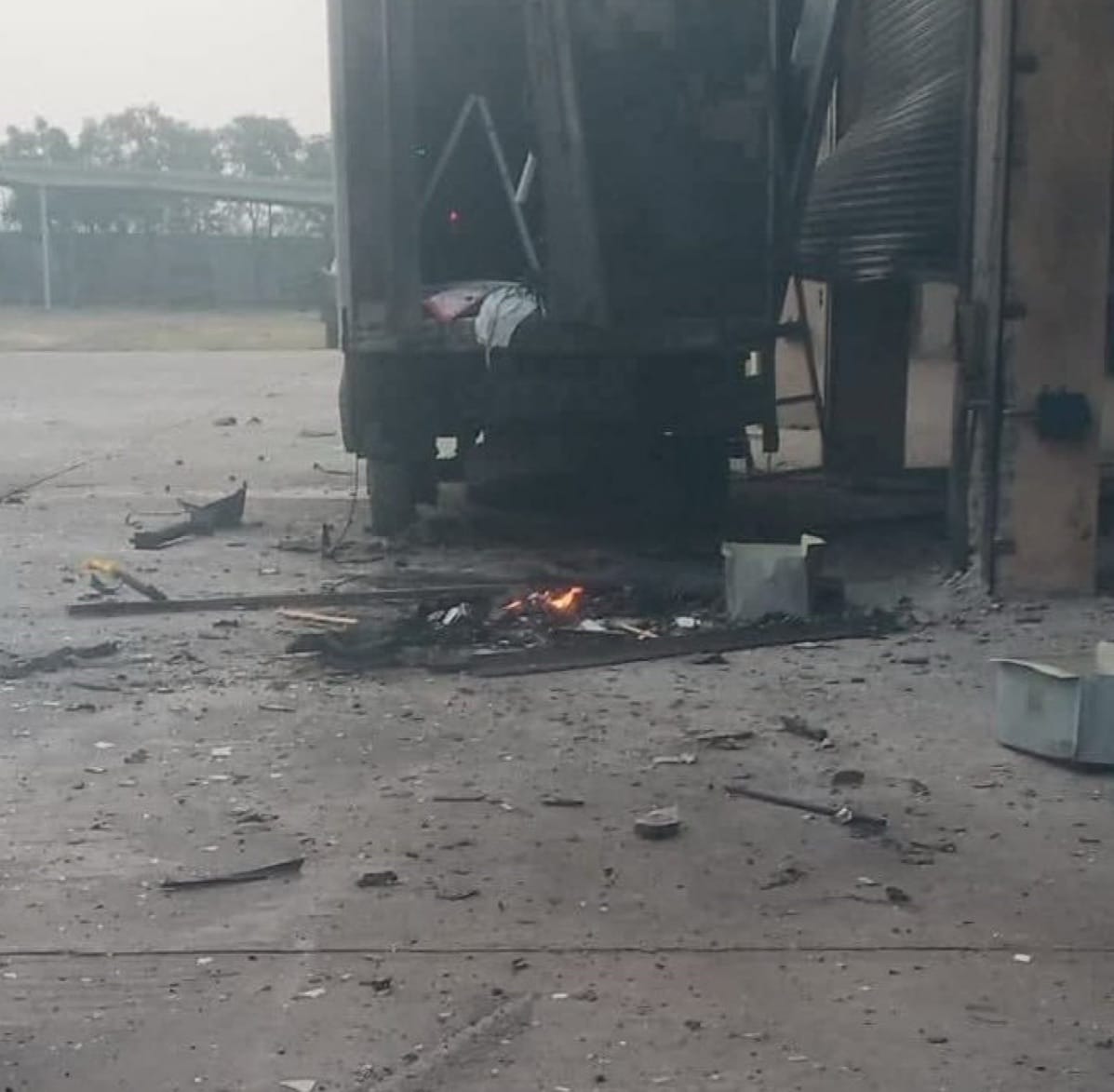 Smoking debris and a small fire scattered beneath a damaged building.