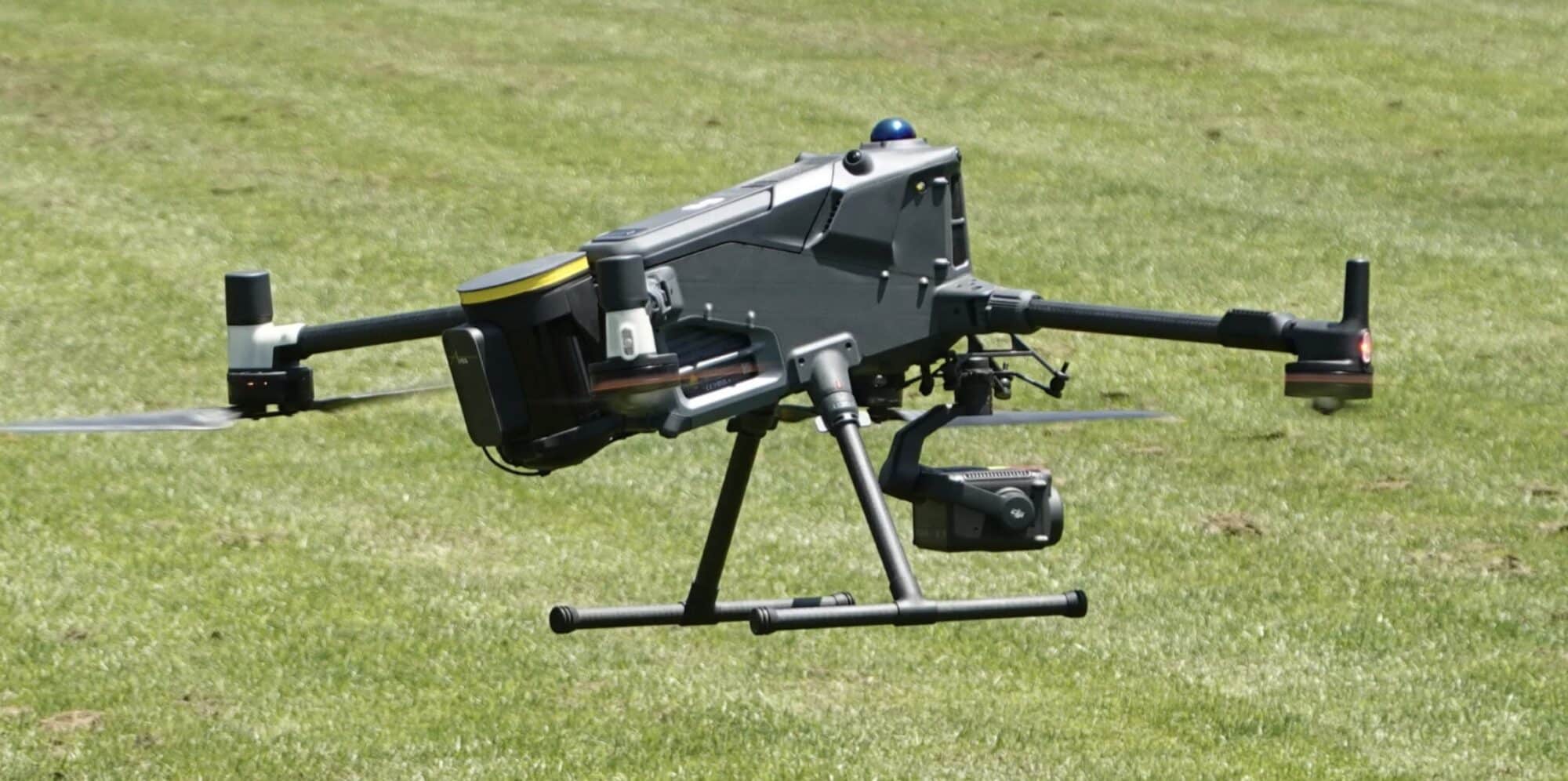 Matrice 400 with its parachute pod fitted, parked on a mown grass field.