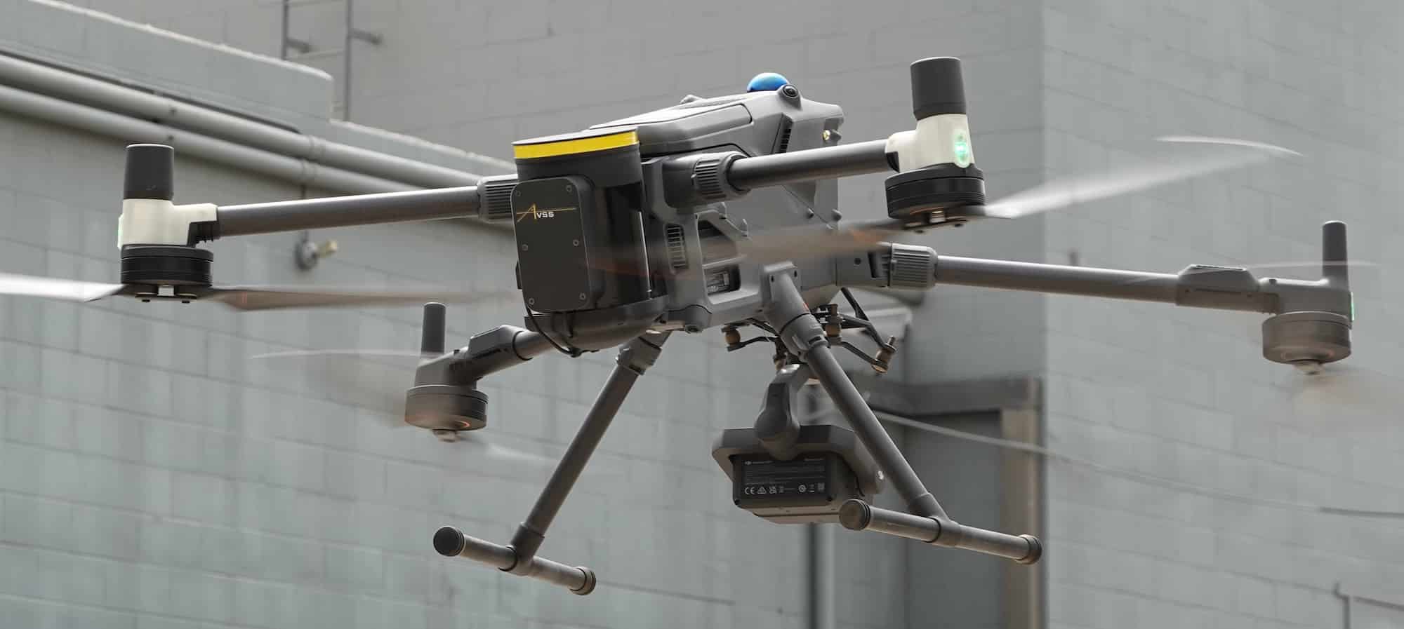 Matrice 400 hovering indoors with the parachute canister mounted above its arms.