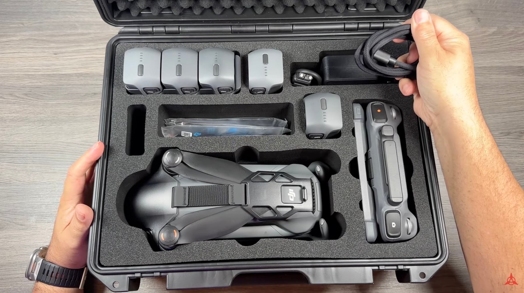 Hands opening a foam-lined hard case holding a folded Mavic 4 Pro and batteries.
