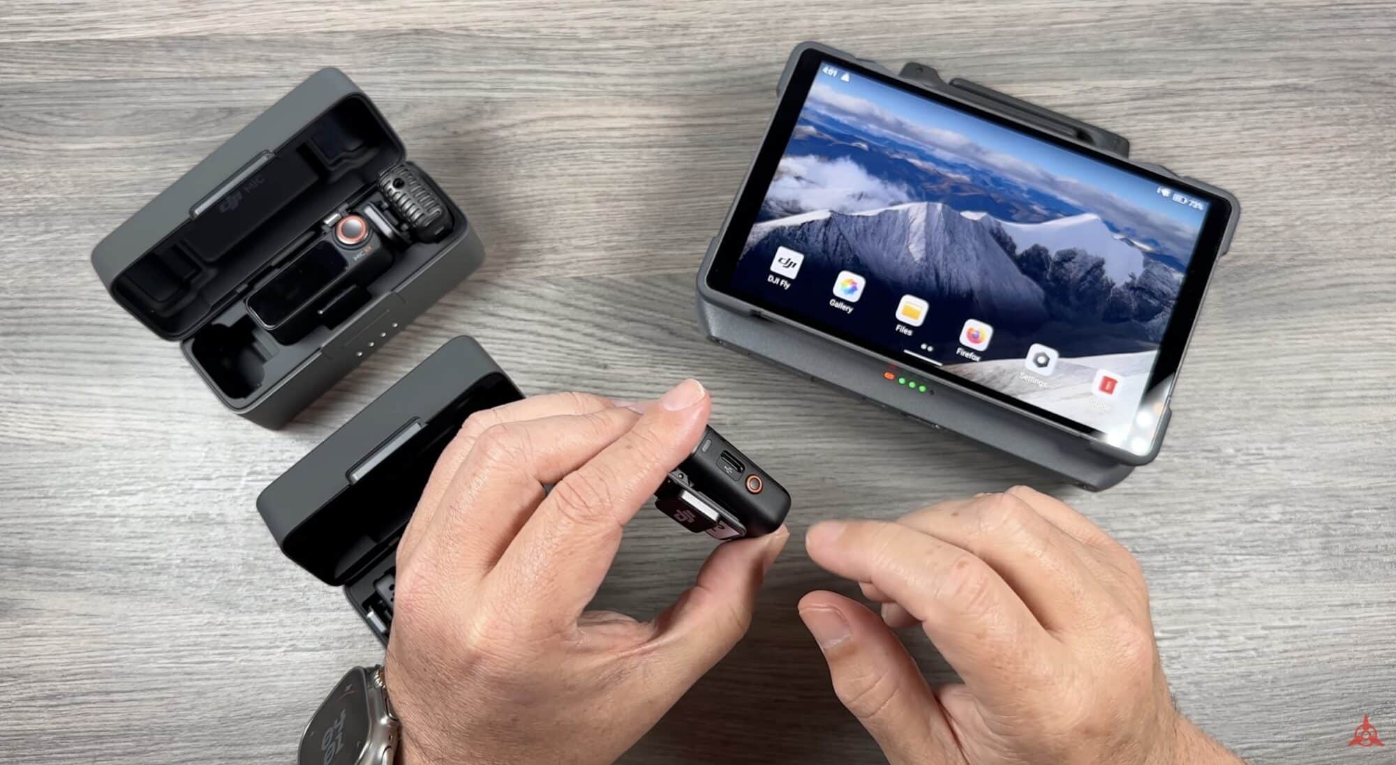 Hands holding a DJI Mic transmitter beside the RC Pro 2 controller.