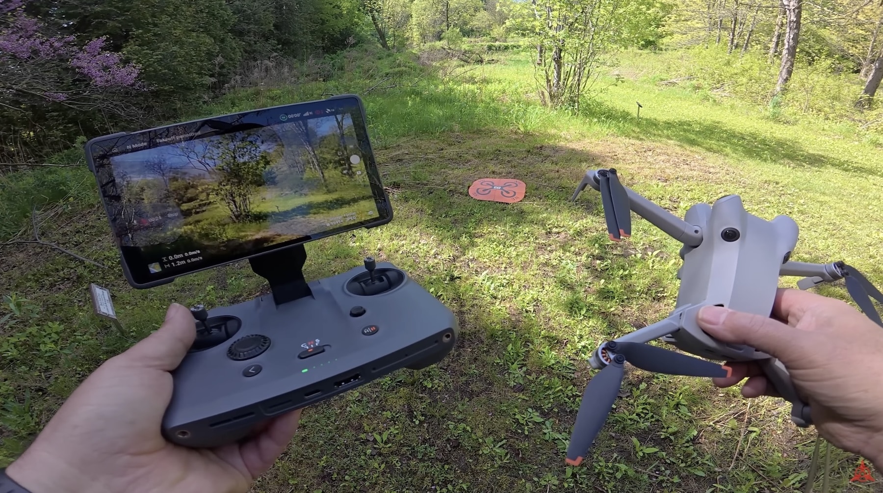 Hands holding the RC Pro 2 controller and a Mini 4 Pro outdoors.