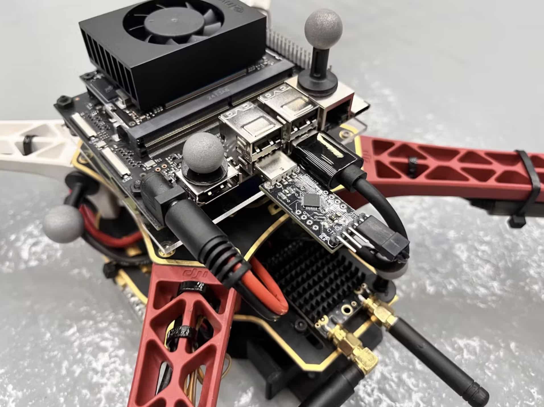 Jetson computer and cameras mounted on a red-framed research quadcopter.