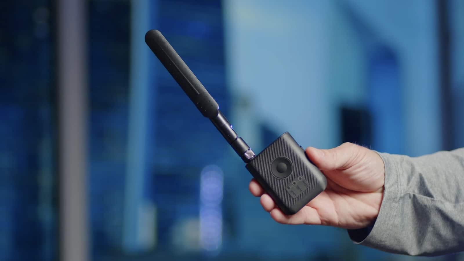 A hand holds the black Ryder Remote ID receiver with its antenna extended.