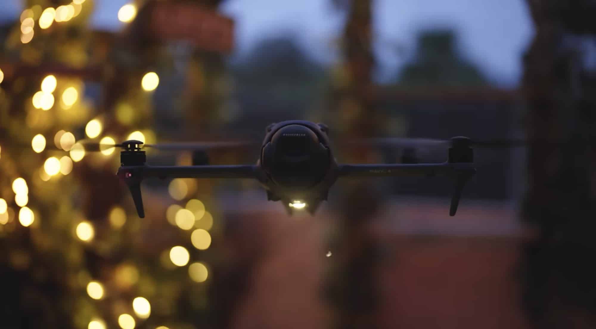 The drone flies at dusk past strings of golden bokeh lights.