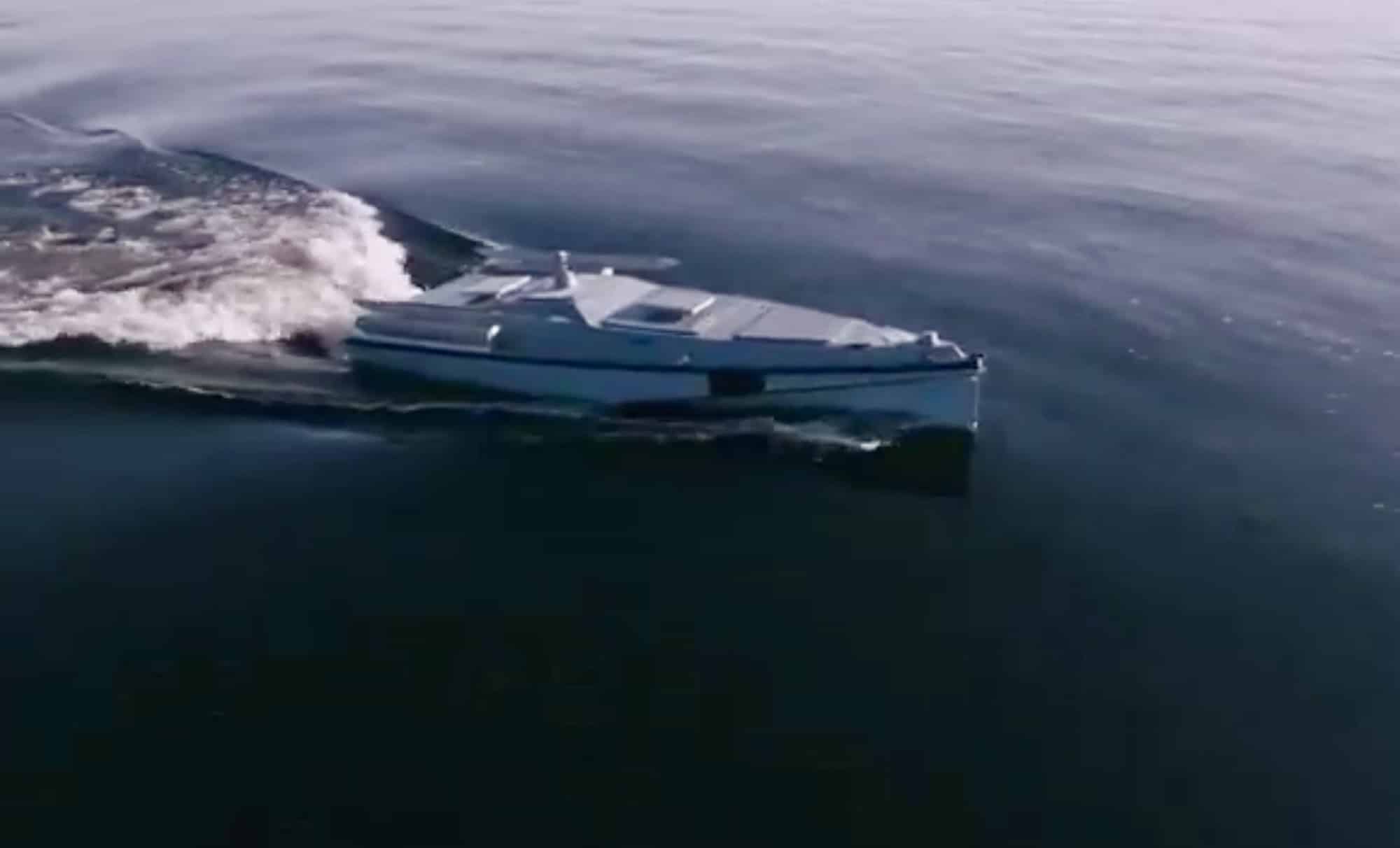 A low-profile uncrewed attack boat throws a wake as it races across open sea.
