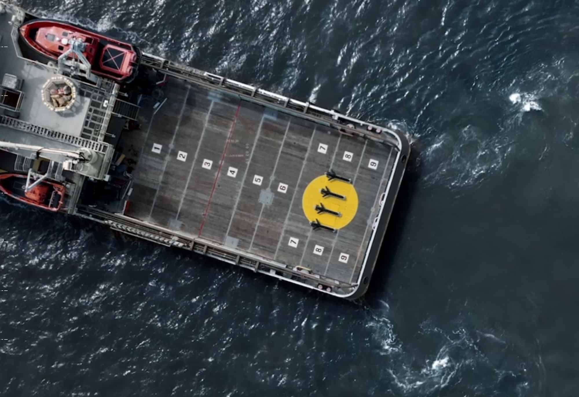 Aerial view of a yellow underwater glider secured on a support vessel deck.