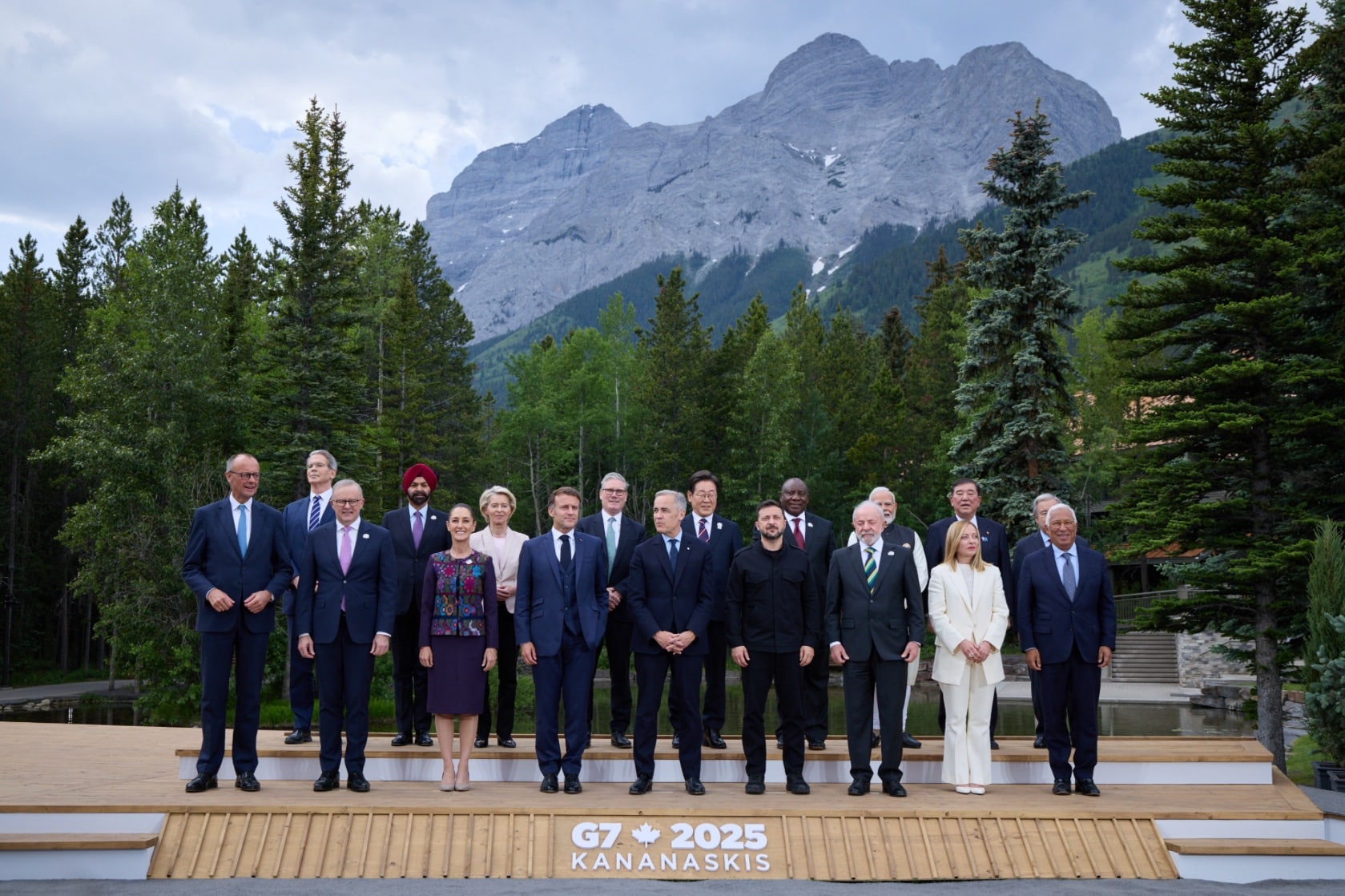 Leaders lined up for the G7 2025 Kananaskis family photo below a mountain.