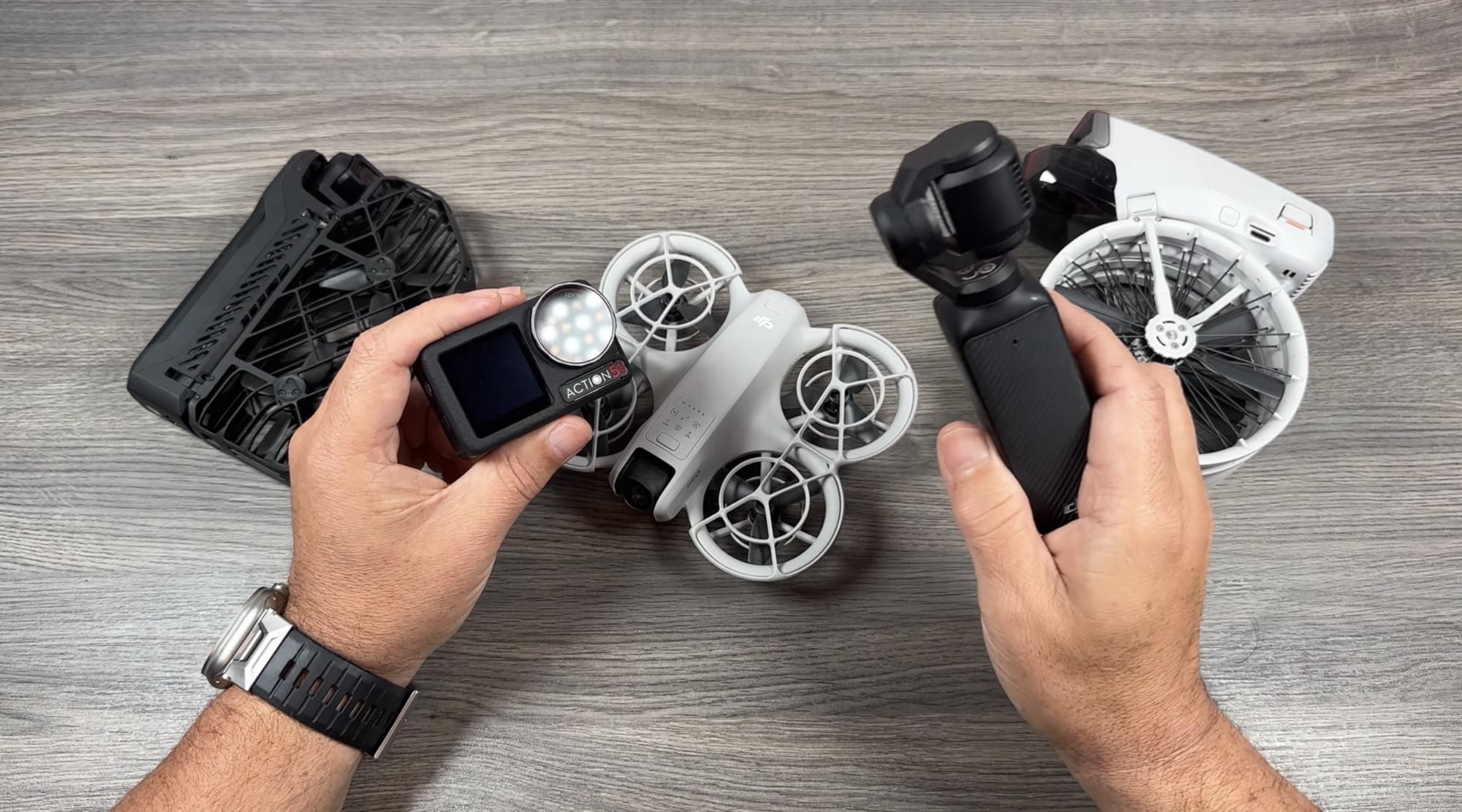 Hands lift a DJI Osmo Action 5 Pro and Osmo Pocket 3 above three folded drones.