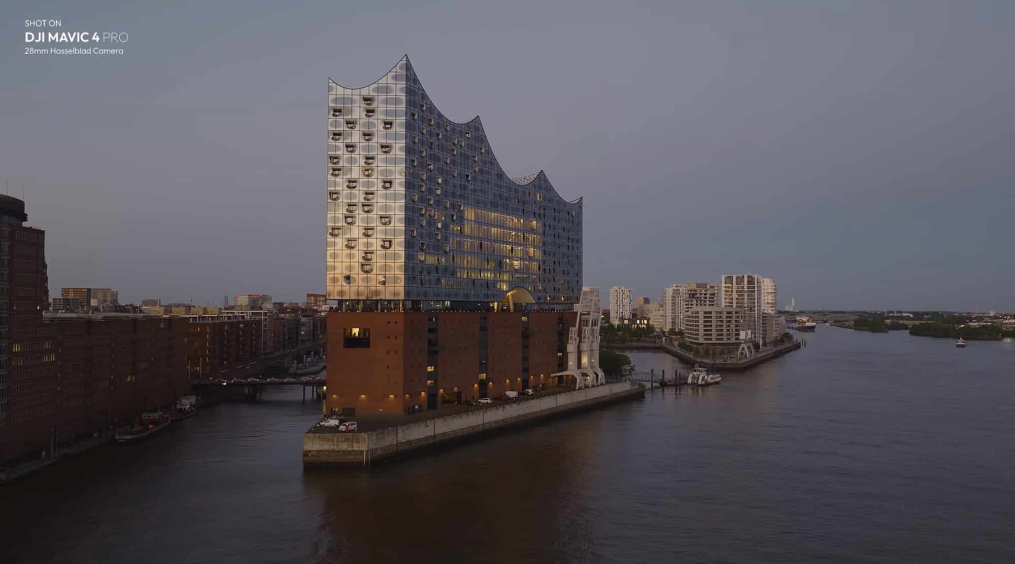 The Elbphilharmonie rising above brick warehouses on the waterfront at dusk.
