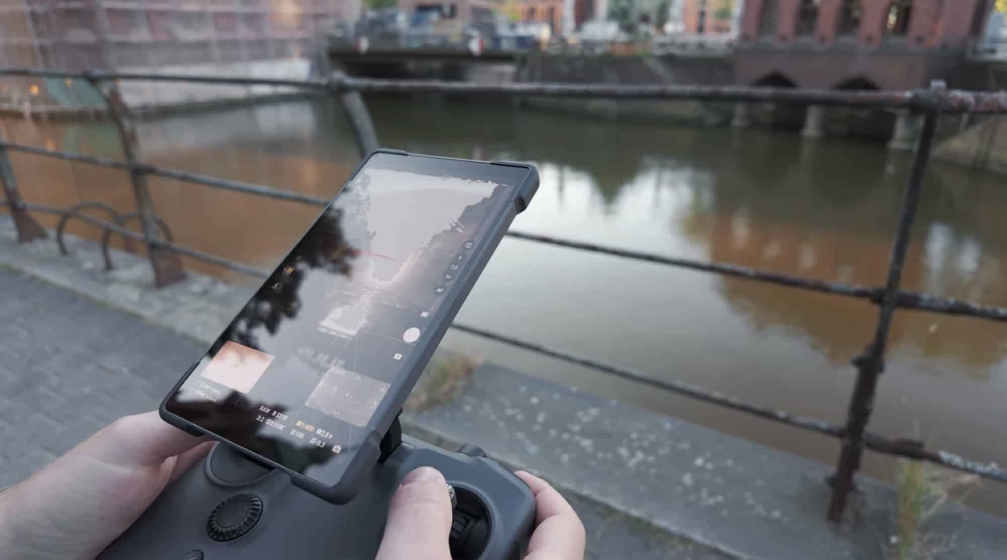 Hands holding the RC2 Pro controller above a canal railing in Hamburg.