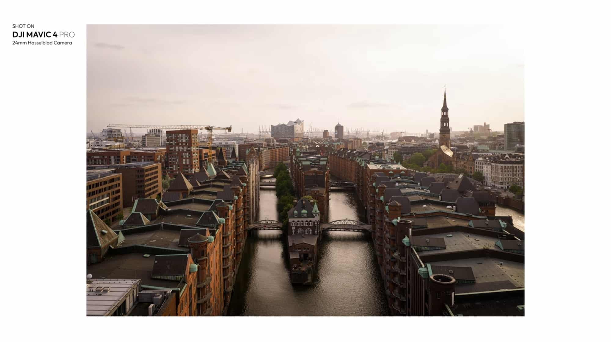 Wide 24mm panorama across Speicherstadt rooftops toward a distant church spire.