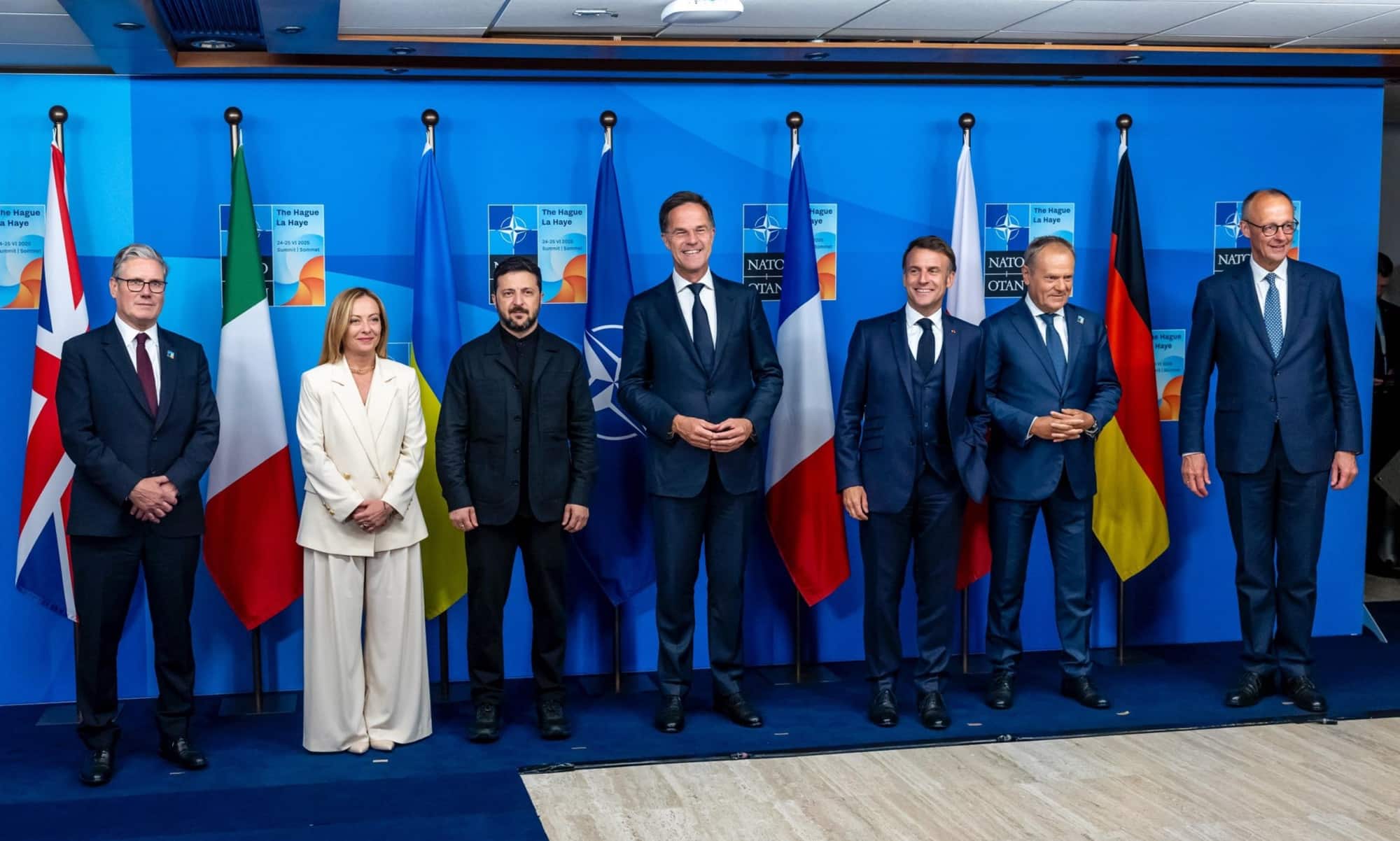 European and NATO leaders line up for a photo before national flags.