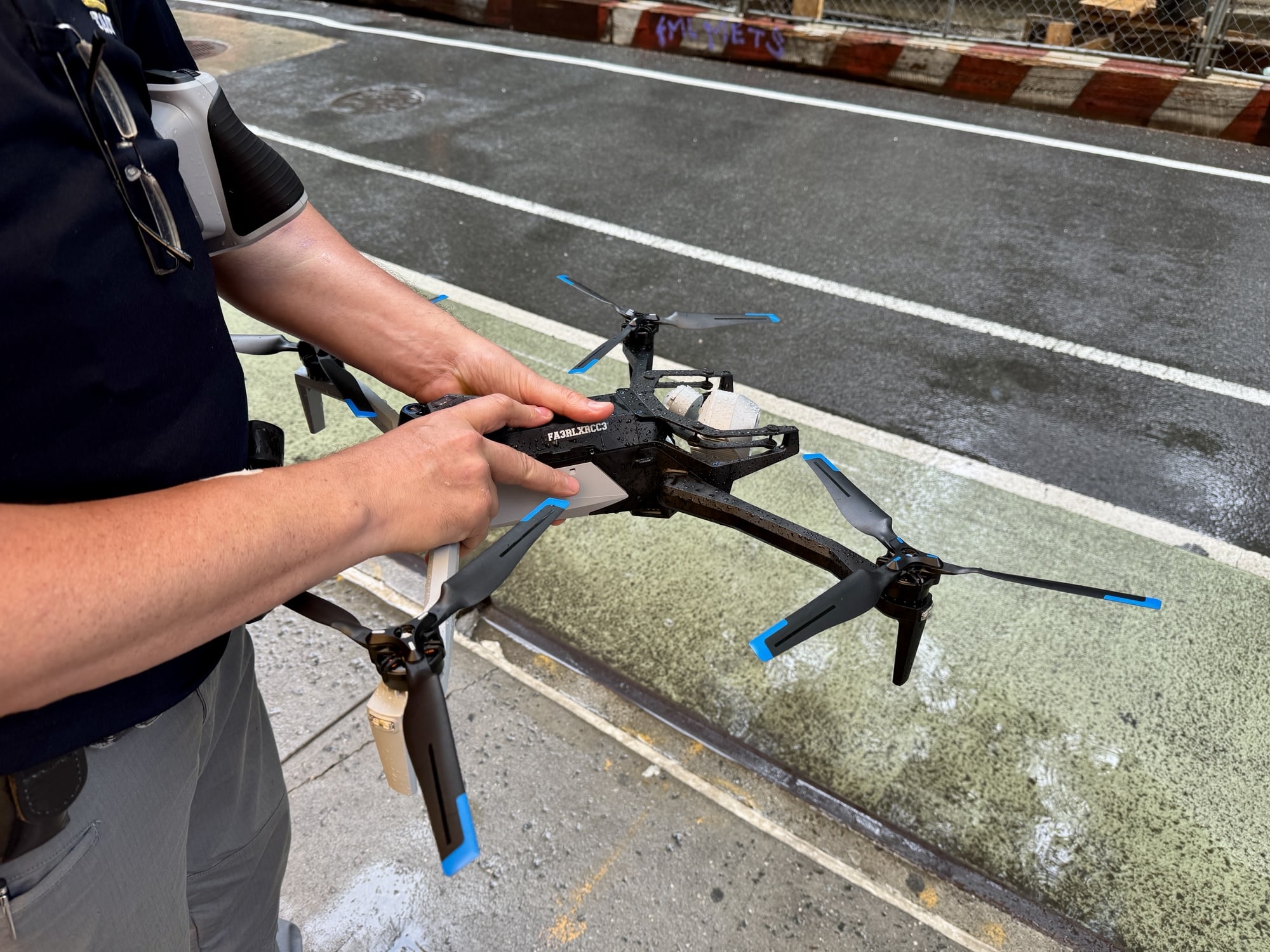 Officer lifting the Skydio X10 by its arms from a wet curb.