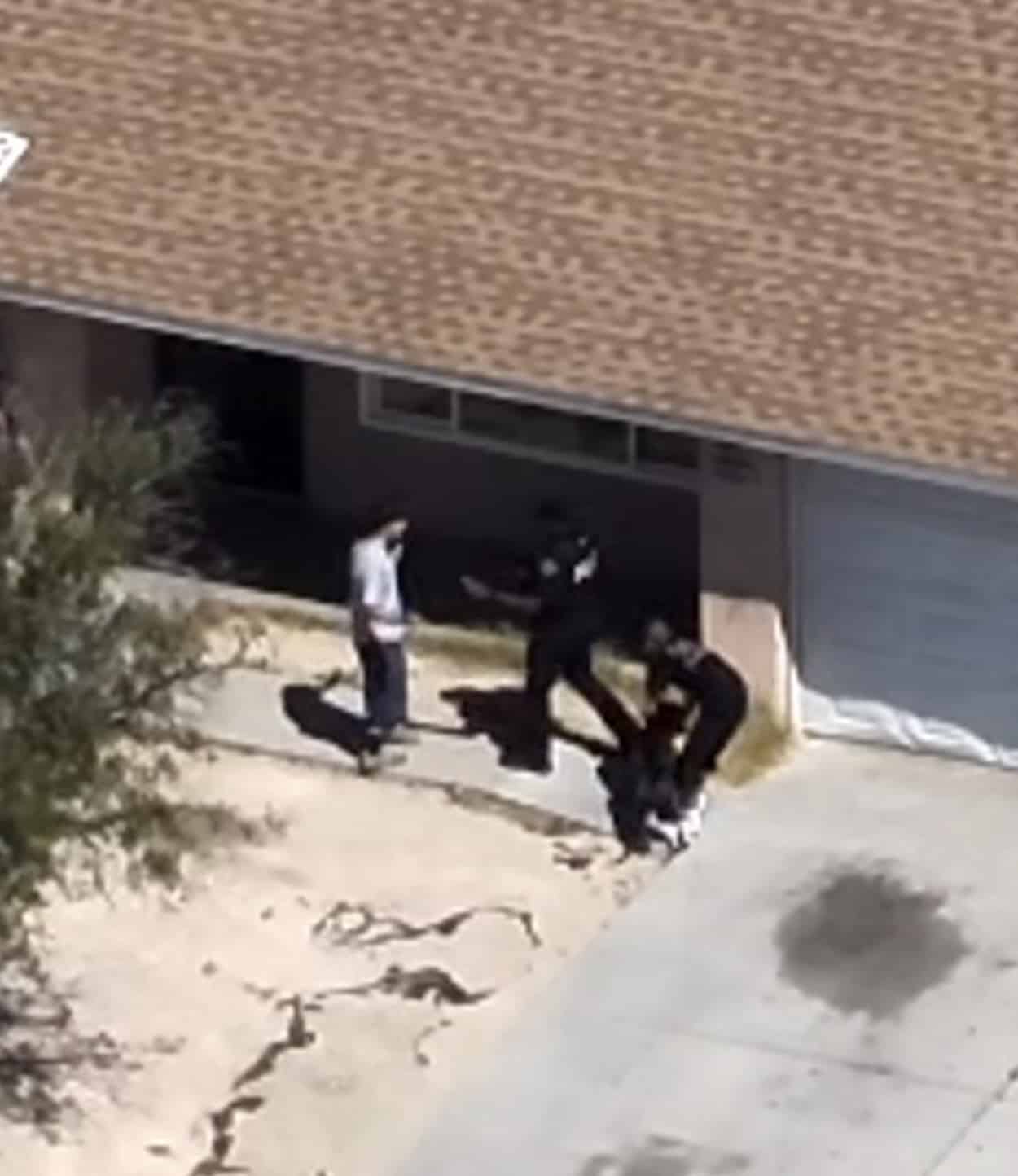 Drone view of officers detaining a rider beside a building wall.