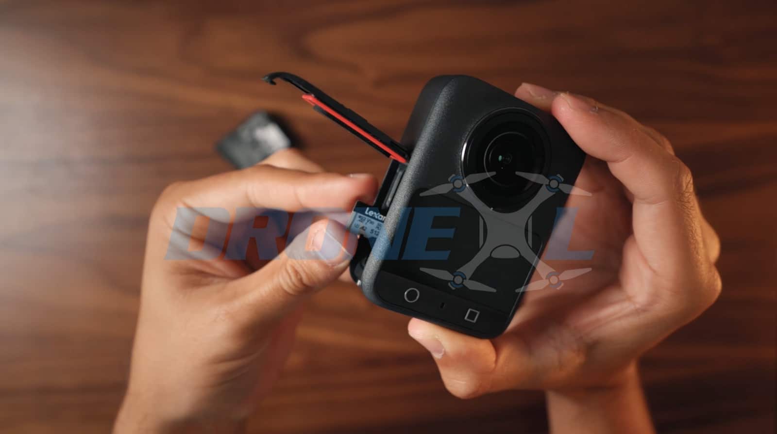 Fingers sliding a microSD card into the slot on the camera's side.