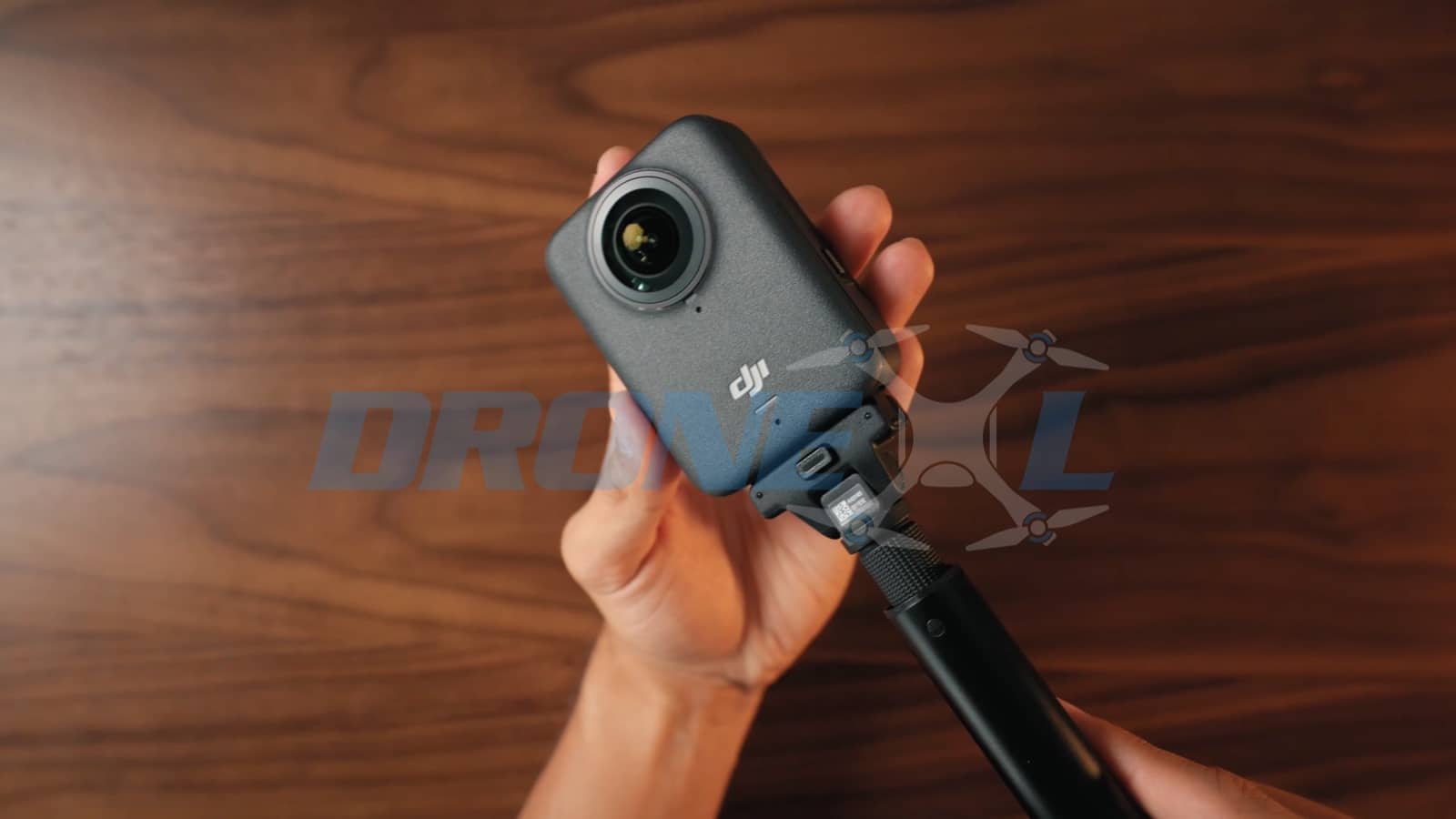 The camera being threaded onto a selfie stick angled down toward the desk.