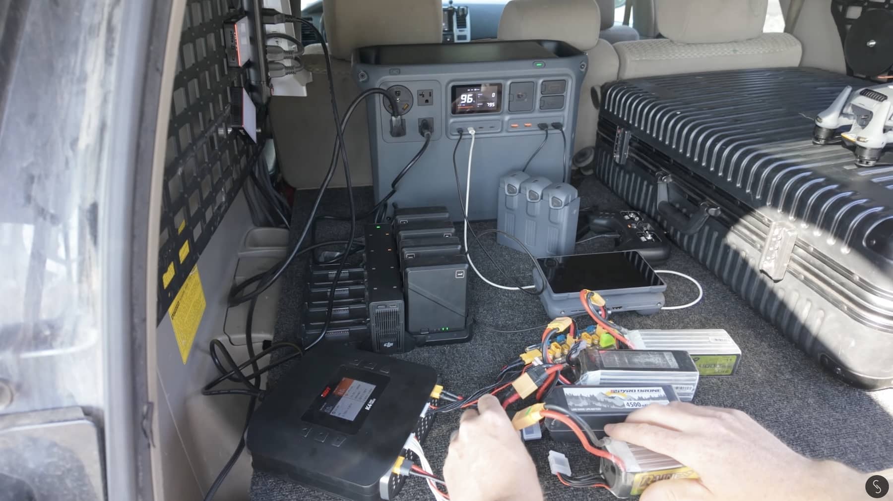 Power station and charging batteries fill the open cargo area of a van.